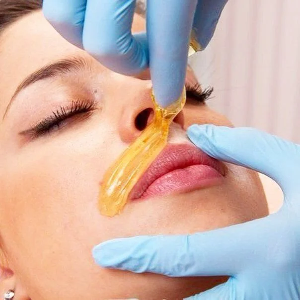 Person waxing the upper lip wearing purple gloves.