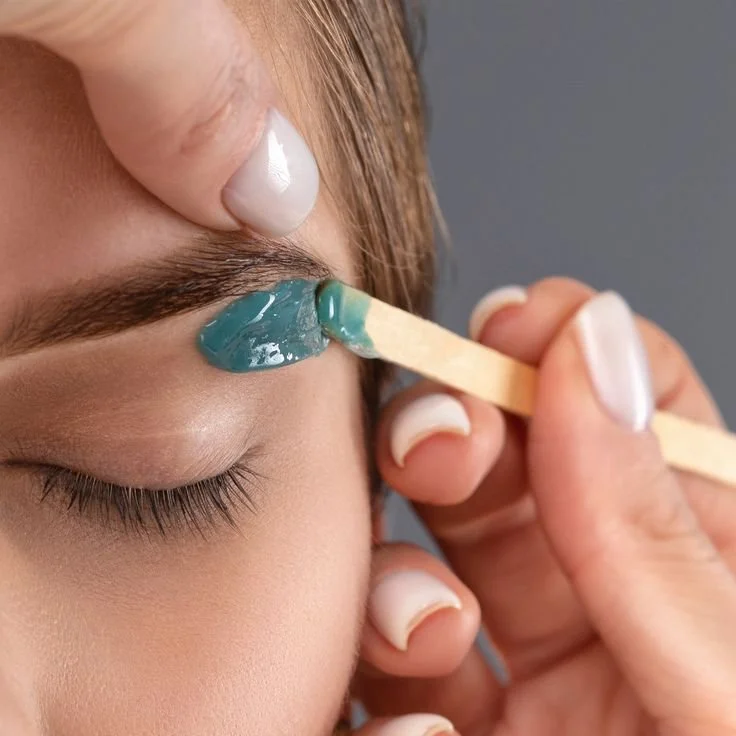A woman receiving a forehead injection from a healthcare professional in a clinical setting.