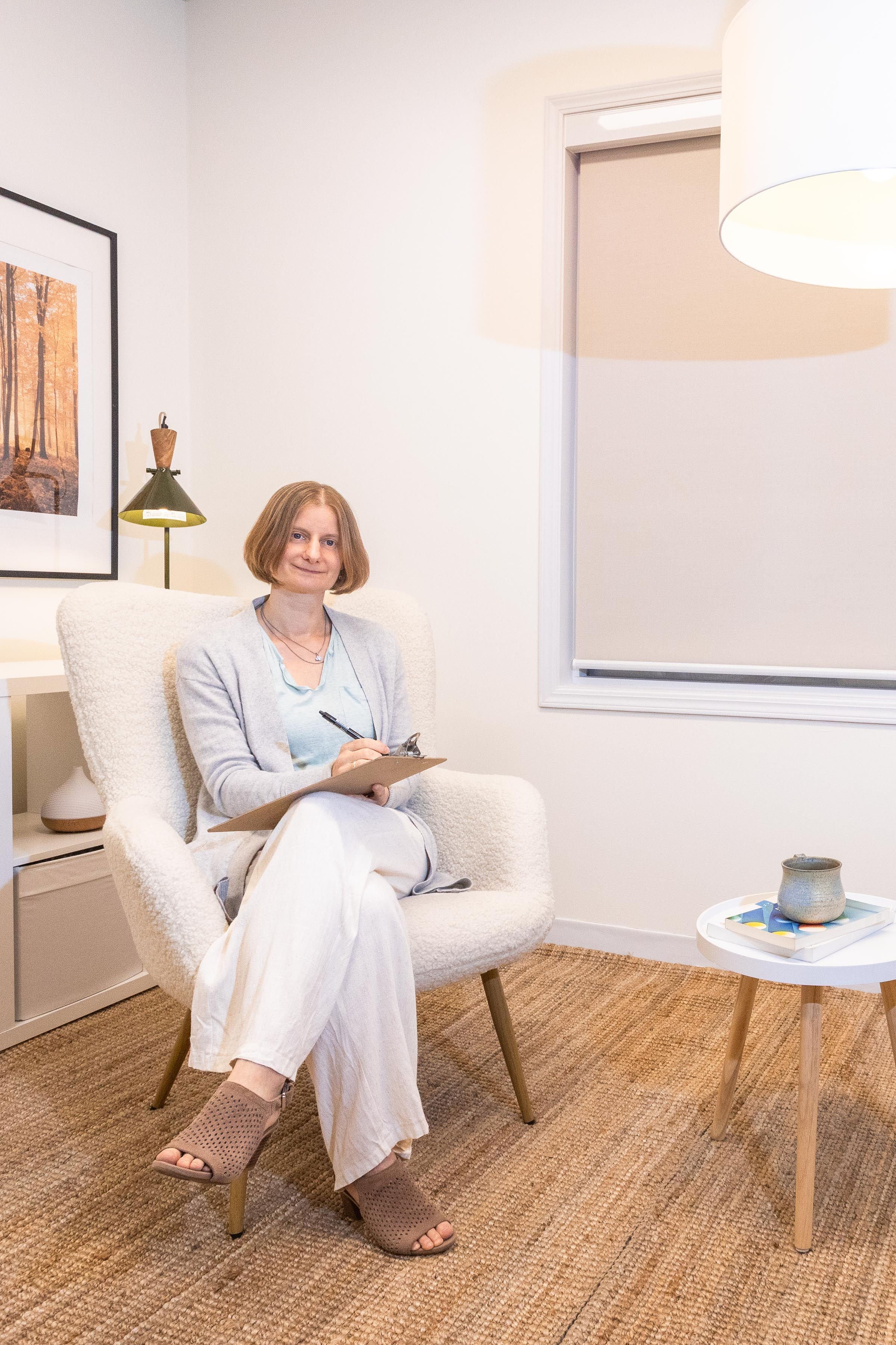 Tina Gal, Registered Psychologist, sitting in her counselling office with a notebook.