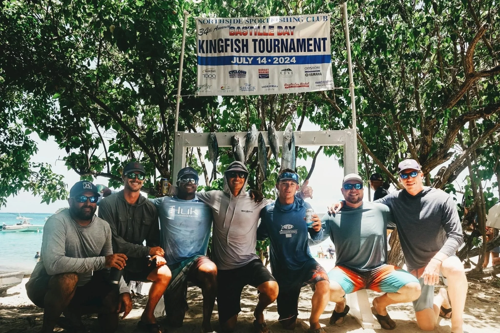 Group of fisher gathered around Bastille Day Tournament Banner for a photo