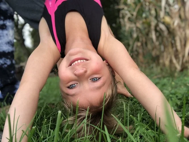 little girl upside down in grass