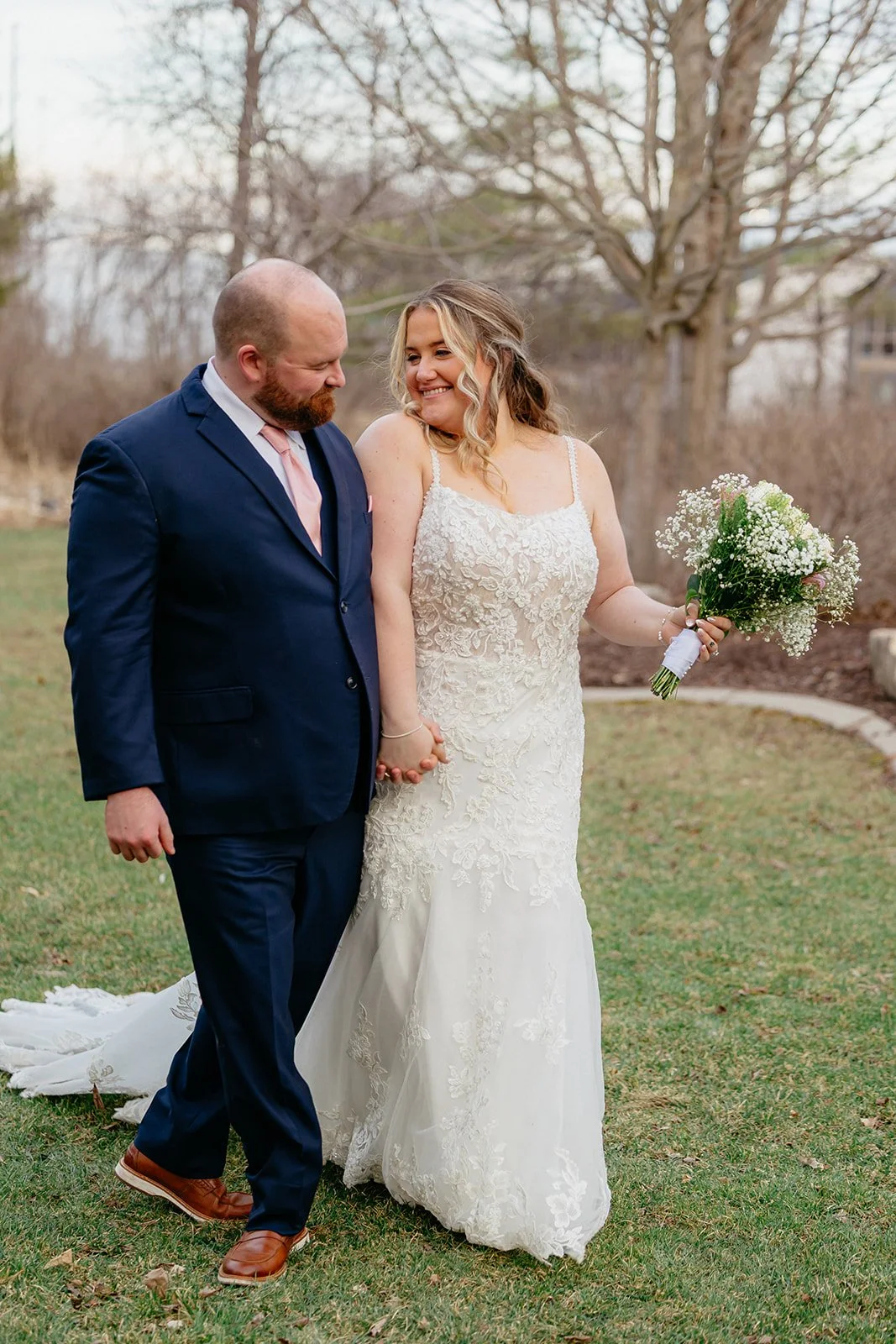 bride and groom walk hand in hand while the bride holds her boquet