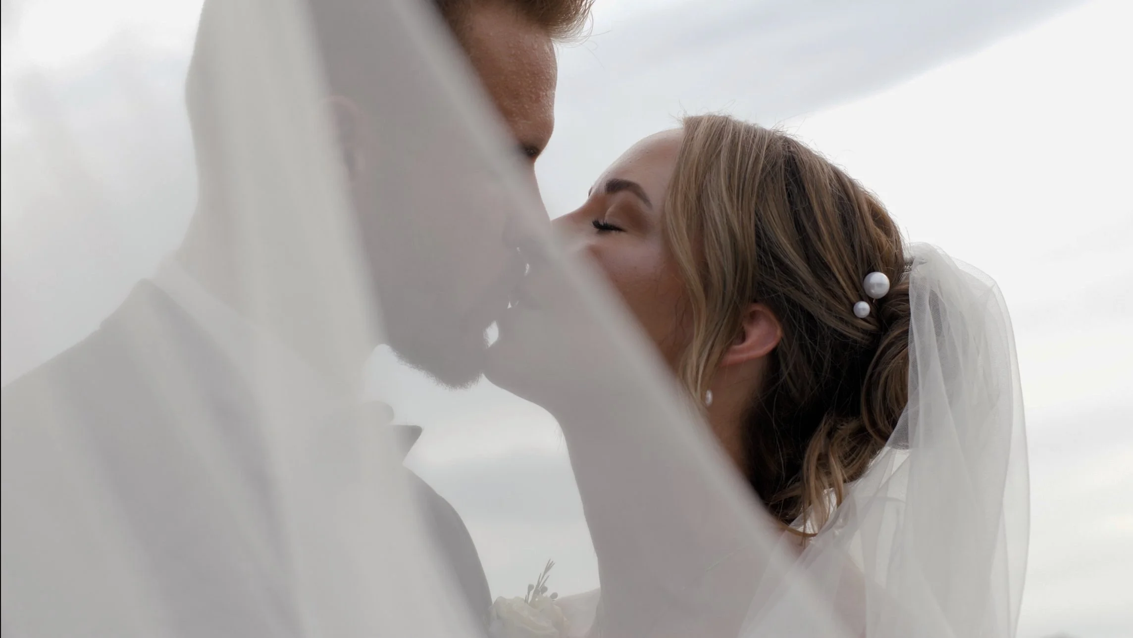 bride and groom kiss under the bride's dress veil
