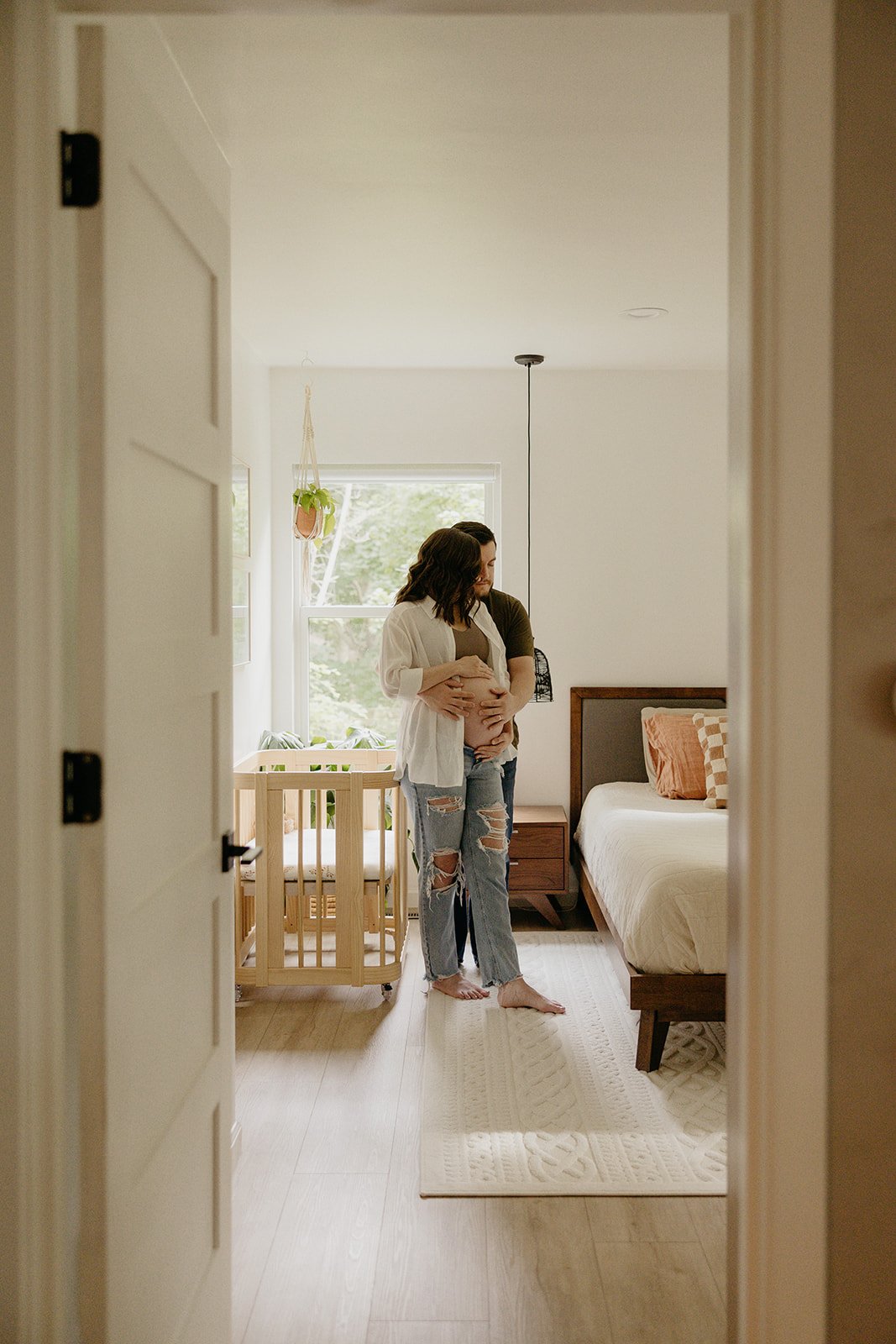 pregnant woman and husband stand by new baby's crib as iowa city photographer captures the moment
