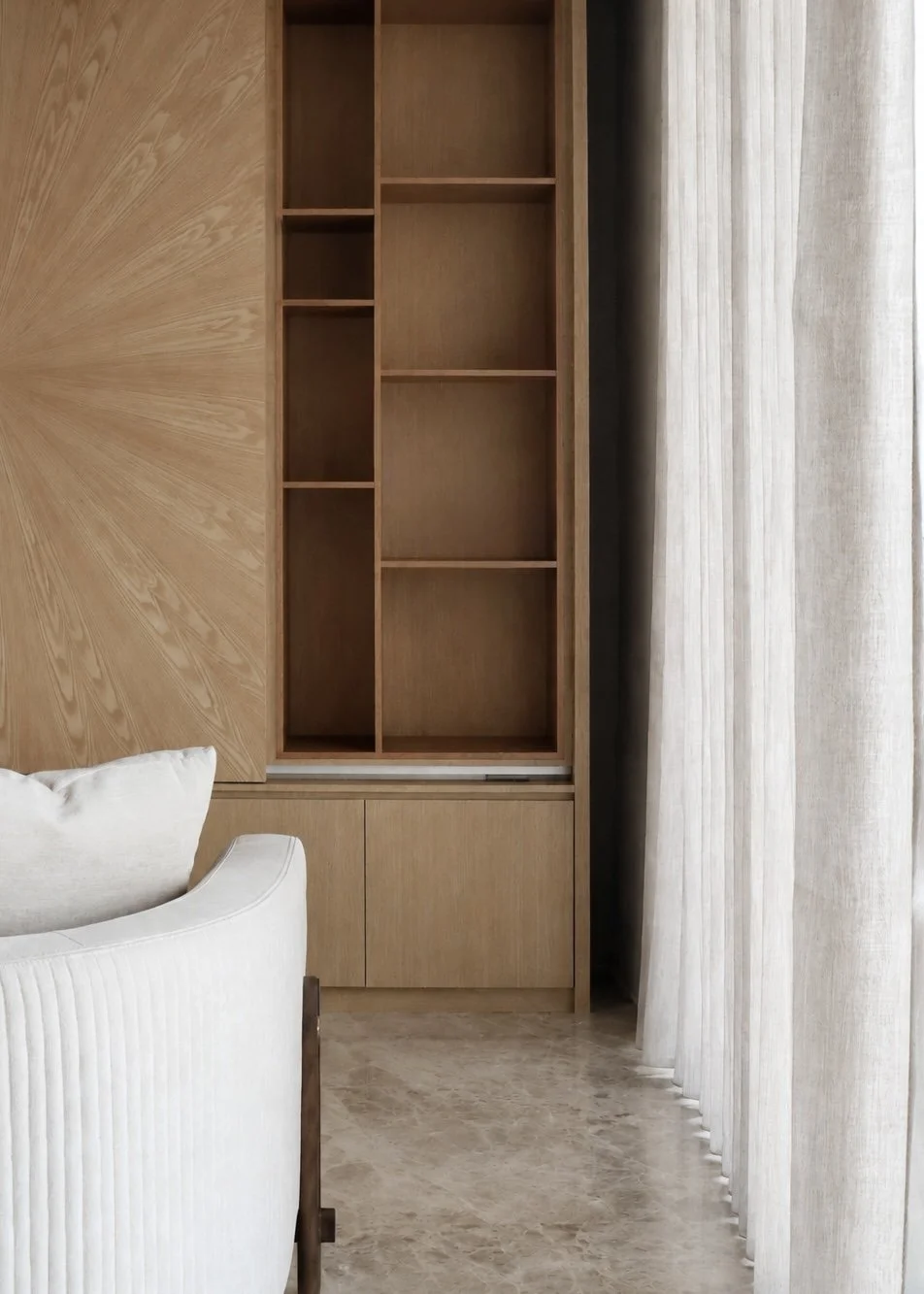 Interior of a room with a wooden cabinet and curtain, part of a white upholstered chair is visible in the foreground.