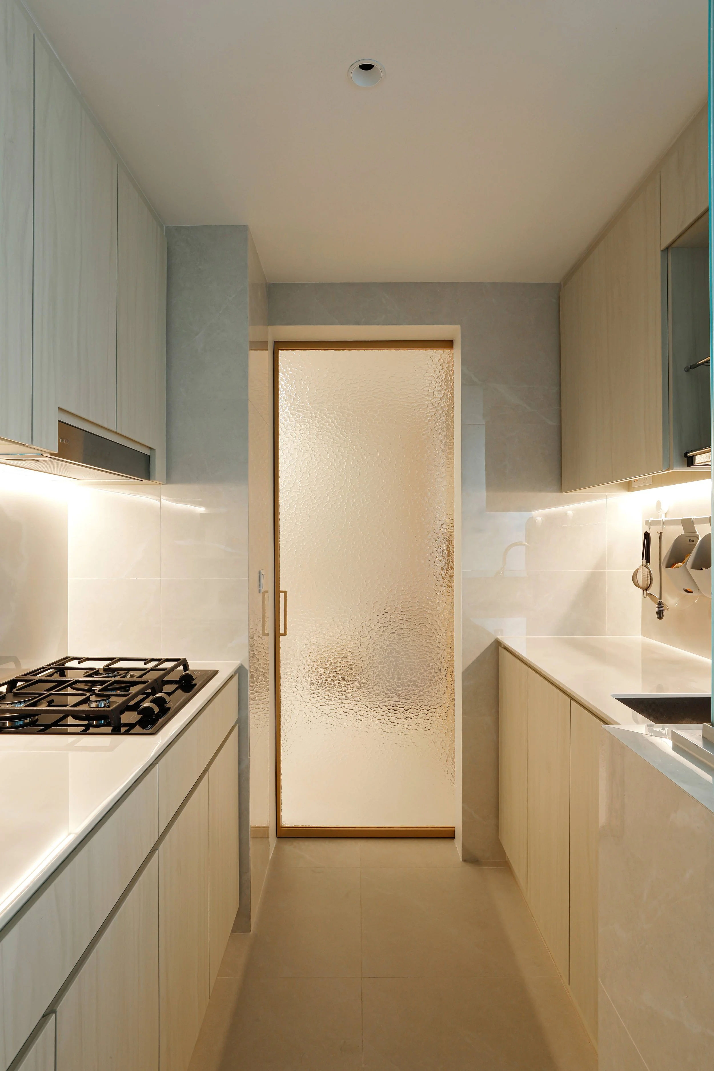 Calm Muji-inspired kitchen with textured glass sliding doors and warm wood finishes at Kovan Melody, Singapore.