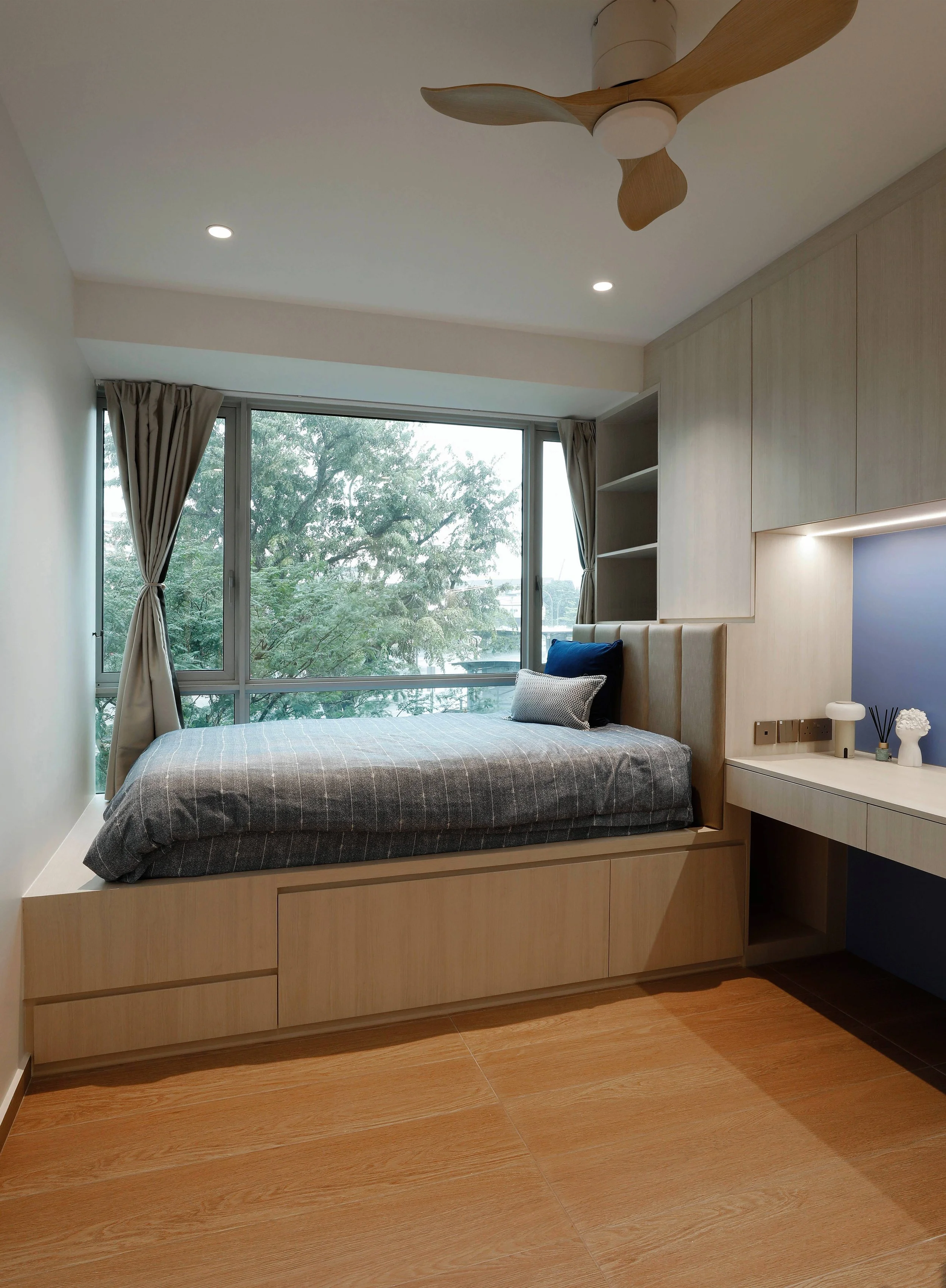 Son’s bedroom with raised timber bed deck and custom wood platform in a warm Muji-inspired Kovan condo interior.