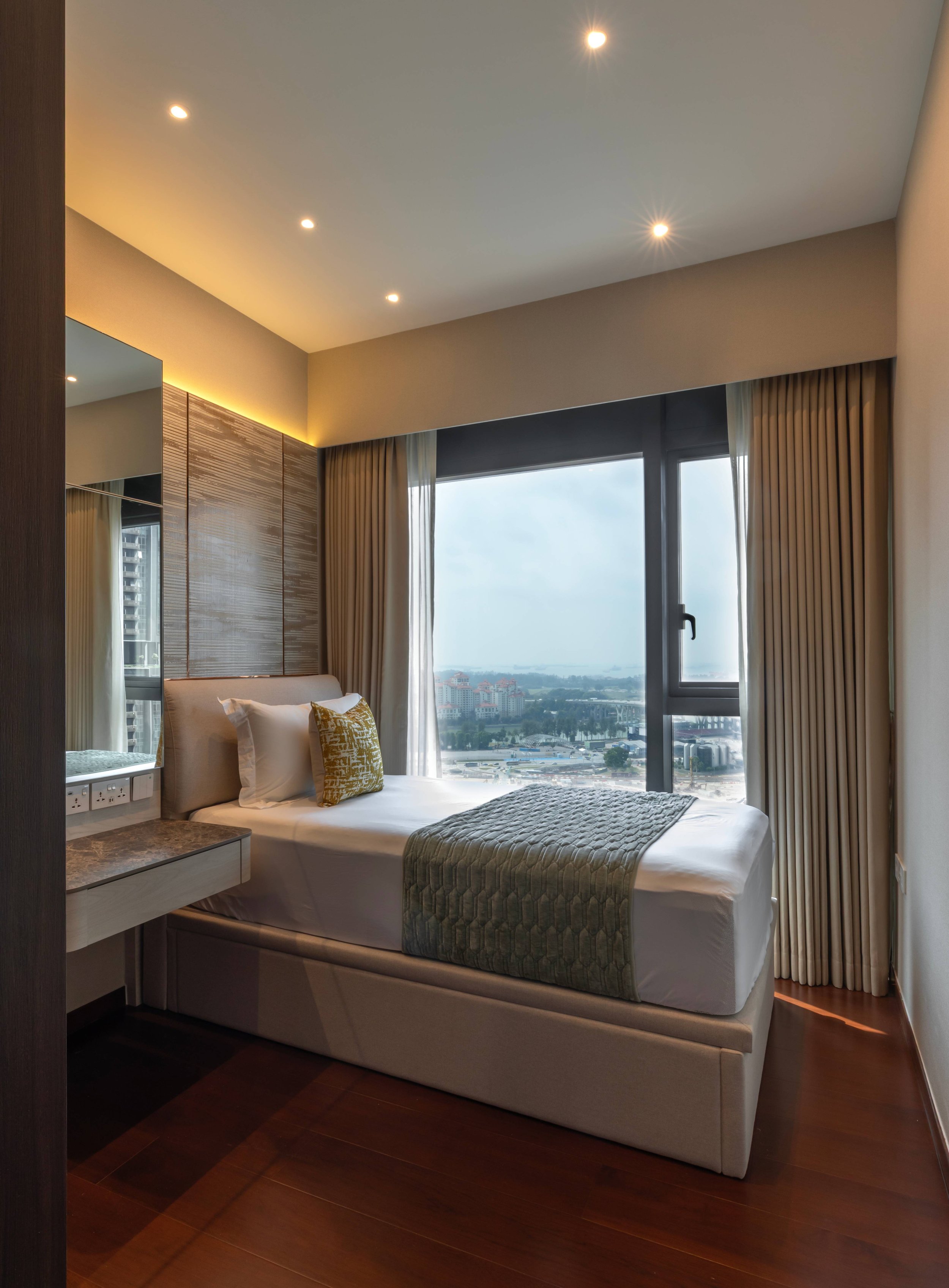 Modern bedroom with a large window, bed with white linens and yellow decorative pillows, beige curtains, and a cityscape view outside.