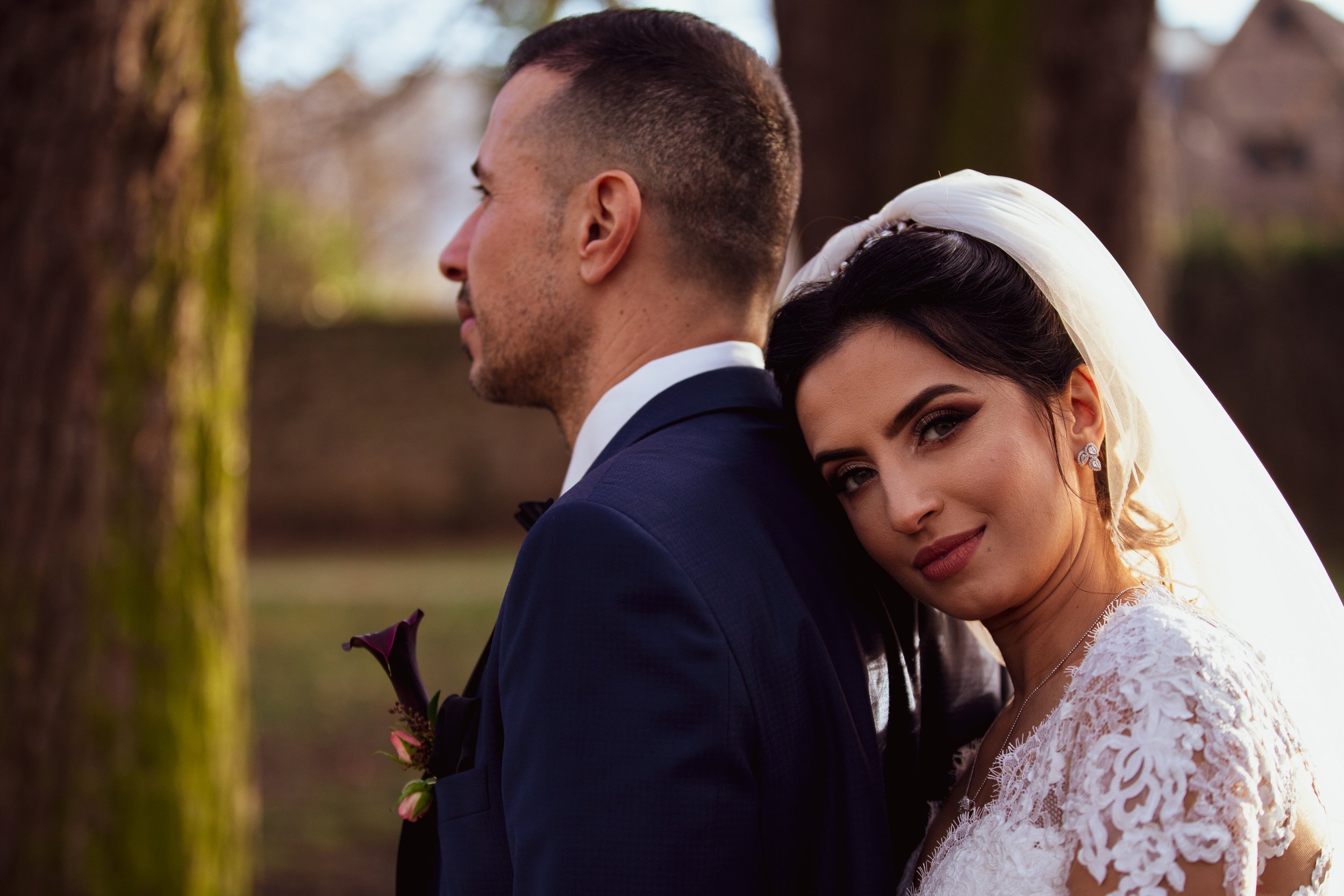 Brautpaar posiert draußen; Braut lehnt an Bräutigam, Hochzeitsporträt.