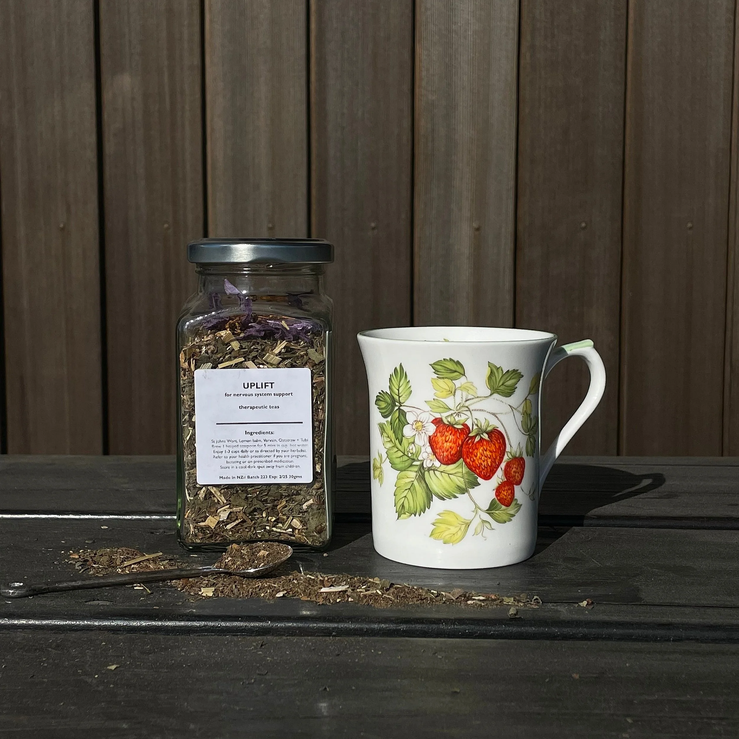 Jar of herbal tea beside a flowery teacup