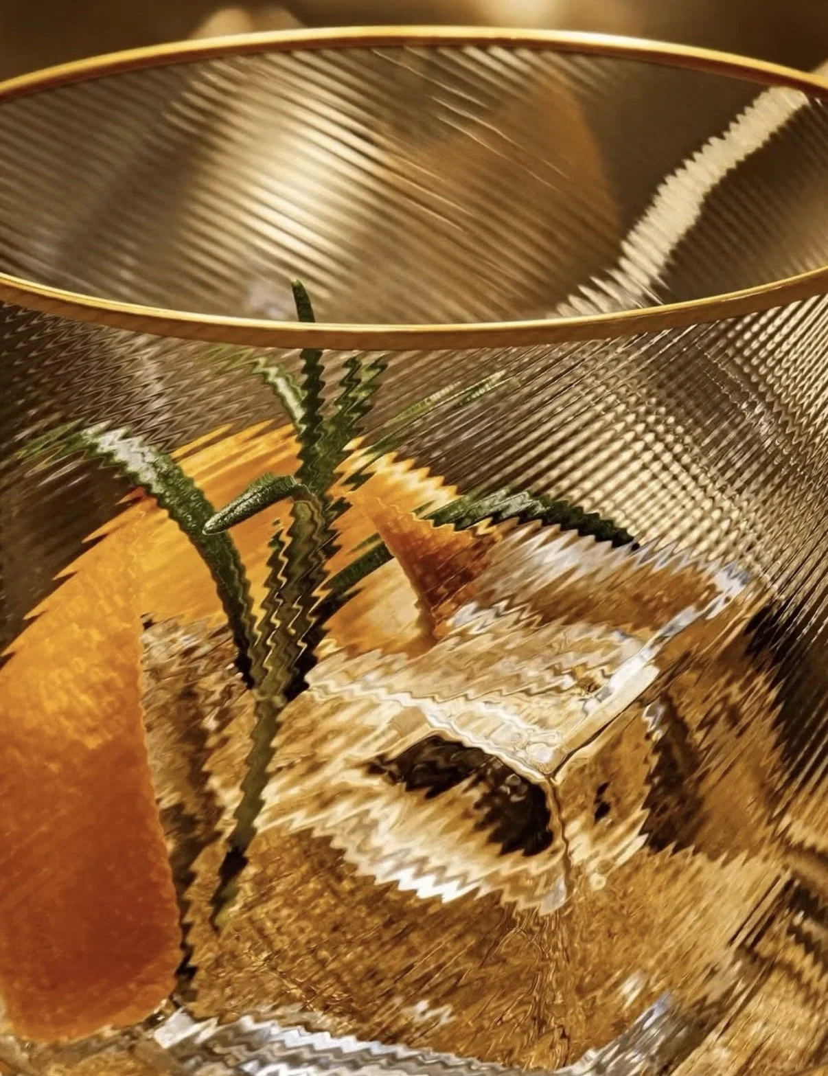 A potted plant with green, spiky leaves inside a textured, golden-colored glass container.