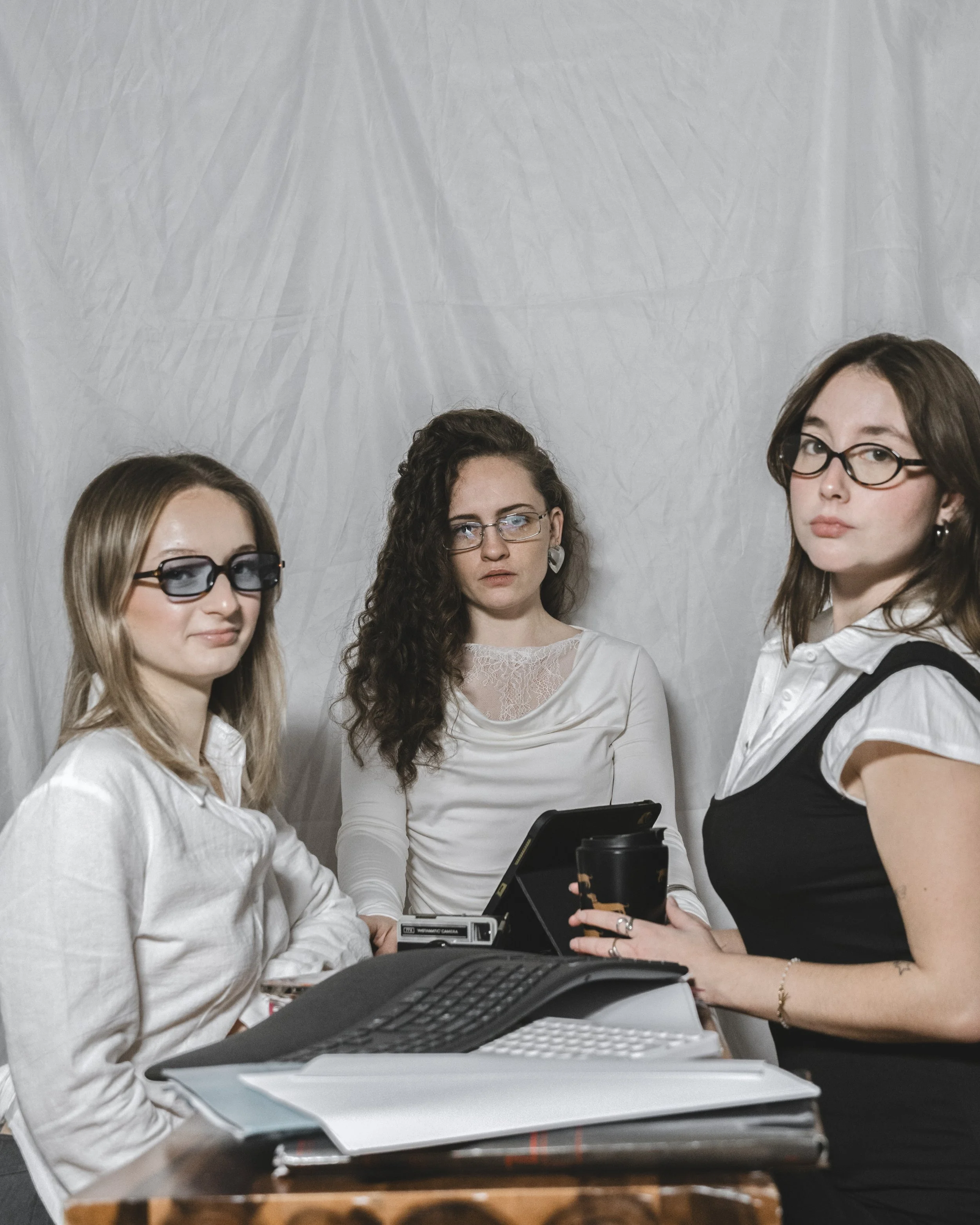 Trois femmes dans un bureau, autour d'une table avec des papiers, un clavier et un écran d'ordinateur