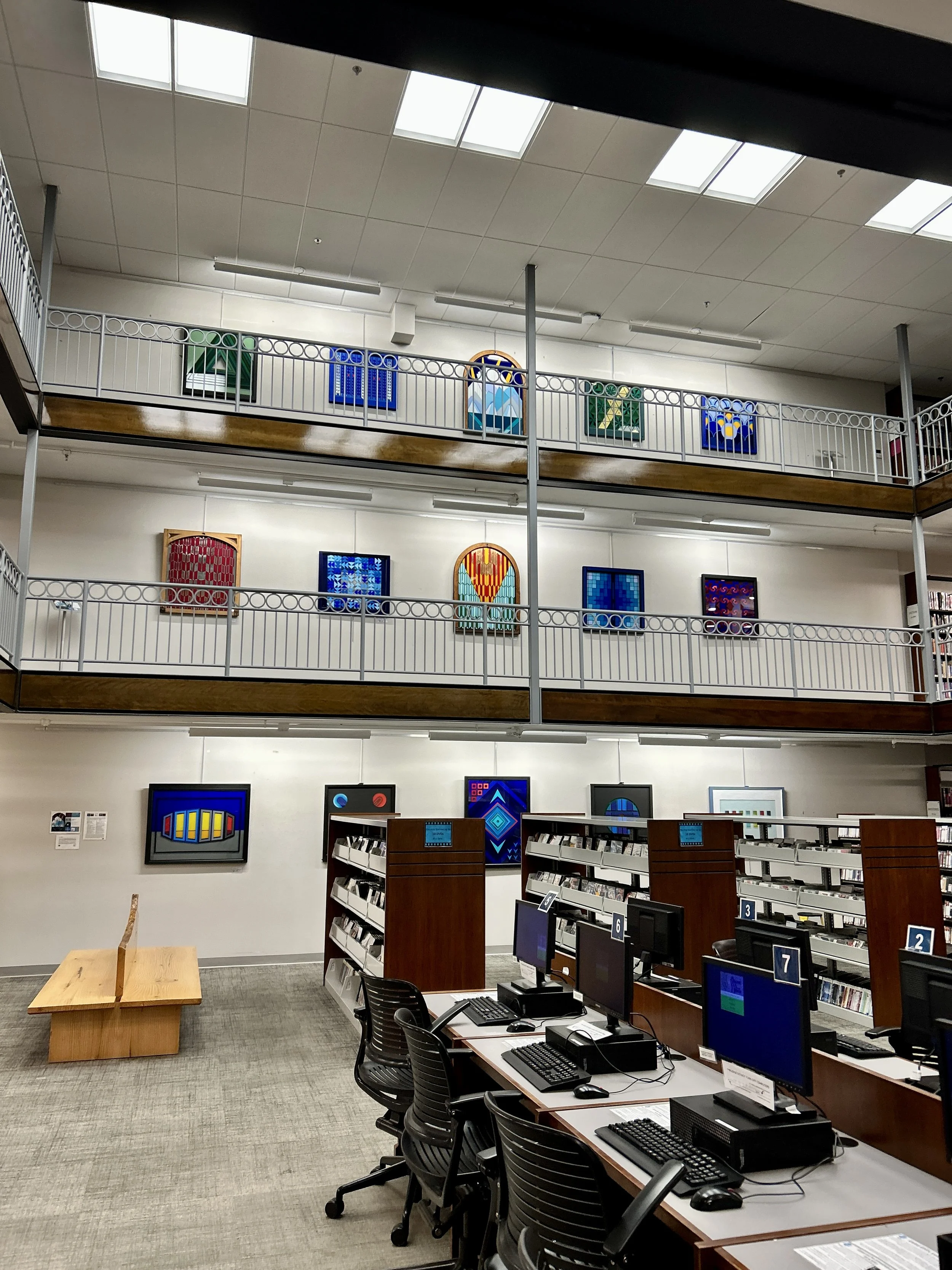 View of computer stations in a library with bookshelves and artwork on the walls.