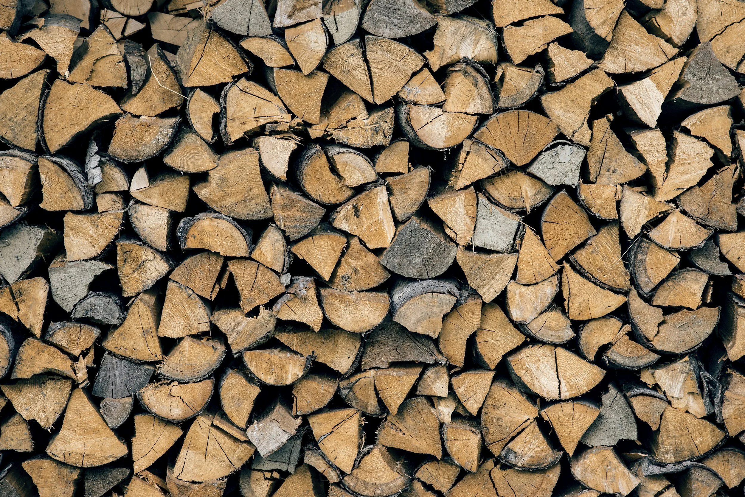 A stack of chopped firewood logs arranged closely together.