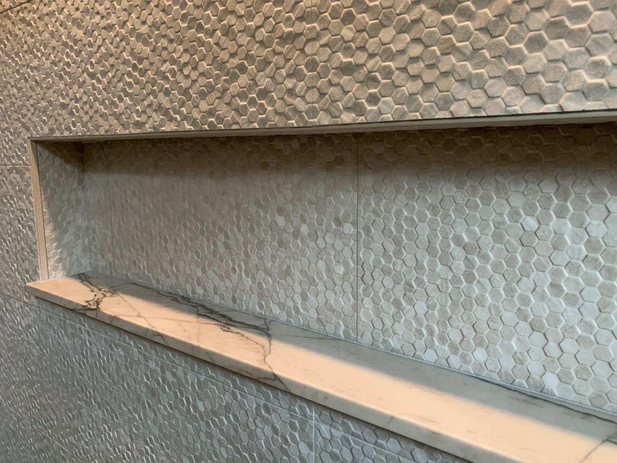 Close-up of a honeycomb textured wall with a marble shelf.