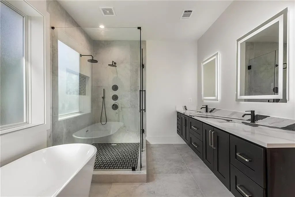 Modern bathroom with a glass-enclosed shower, black fixtures, white double vanity with black cabinetry, and a freestanding bathtub.