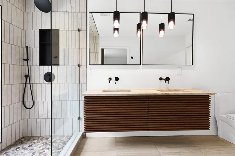 Modern bathroom with a glass shower, black fixtures, a wooden vanity with two sinks, a large mirror, and a white toilet.