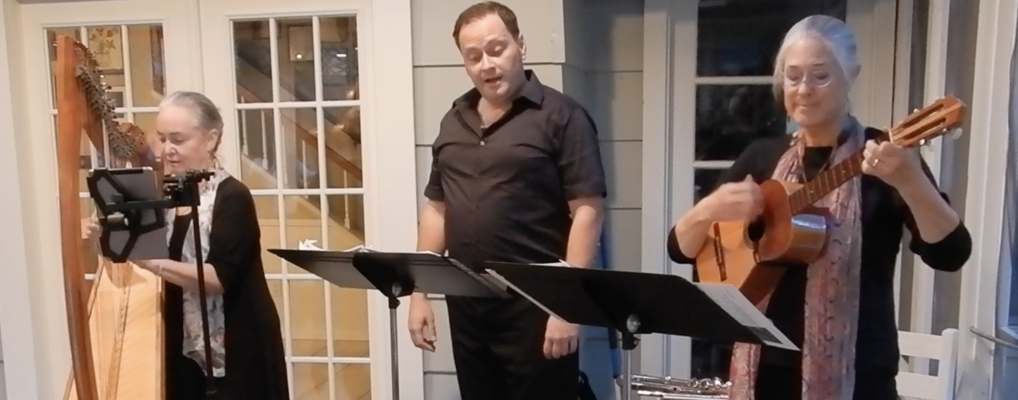 Harpist Shana, singer Trevor Shaw, and Adrienne playing cuatro, performance a house concert on a back patio