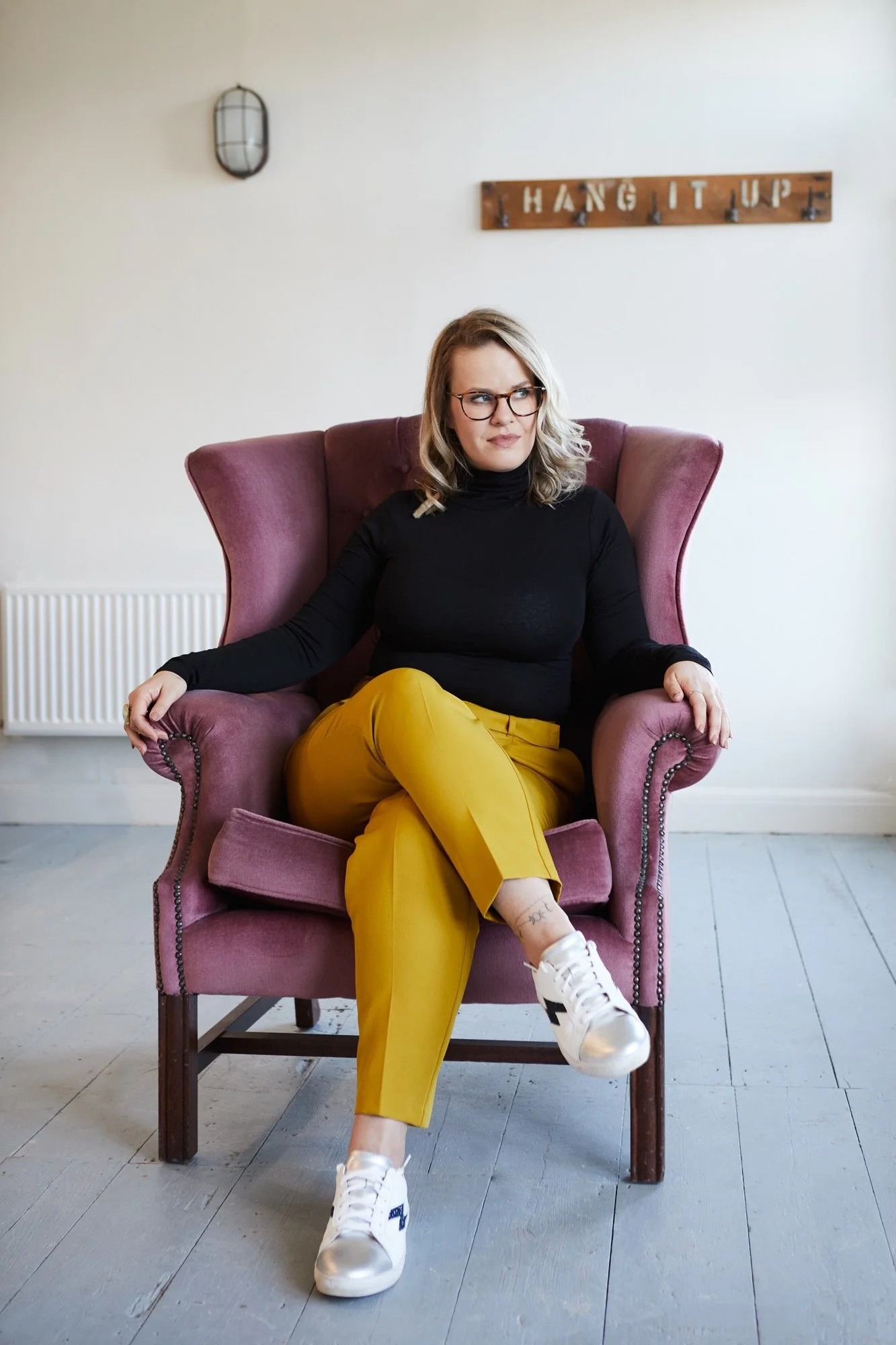 Cherish Amber sex and relationship coach relaxed and smiling in pink velvet wingback chair