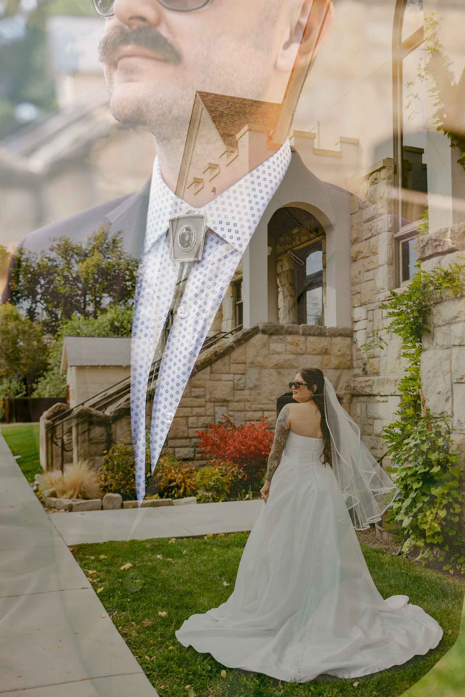 A double exposure photograph combining a close-up portrait of a man in a suit with a mustache and sunglasses layered over a bride wearing a white gown standing outdoors near a stone building, surrounded by greenery and red bushes.