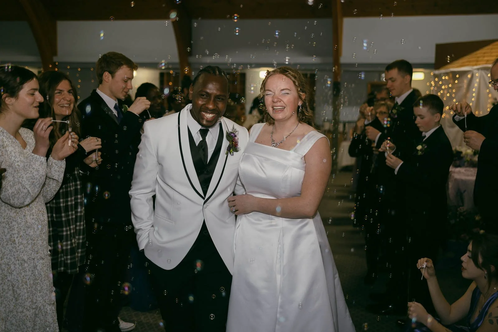 An Idaho wedding celebration with a bride and groom surrounded by friends and family blowing bubbles. They are leaving to begin their life together