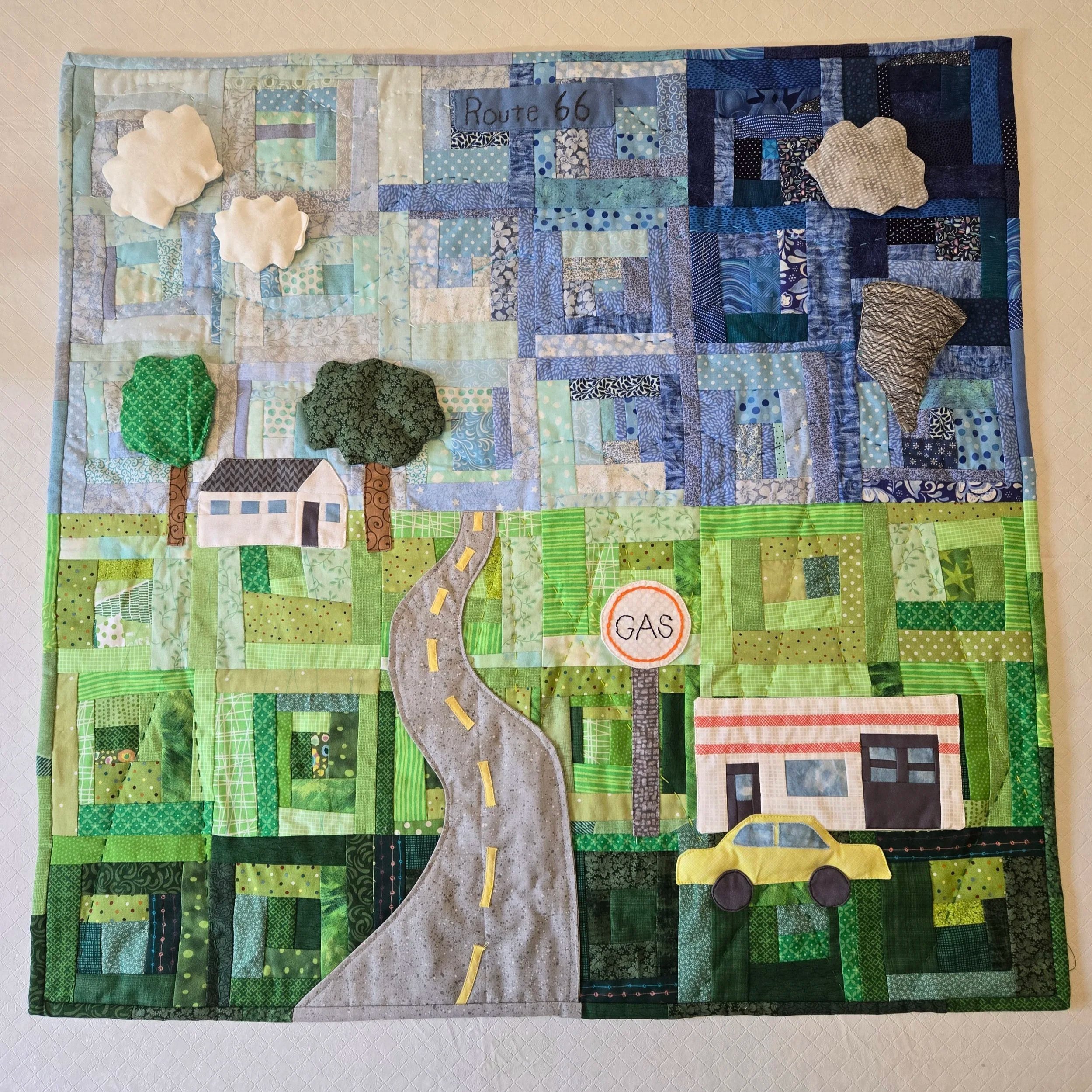 Oklahoma Summer on 66
by Kathy Doss
*
Inspired by many summer drives on Route 66 with storms in the distance.

Scrappy log cabin with flat and puffy applique pieces. Big stitch hand-quilting.