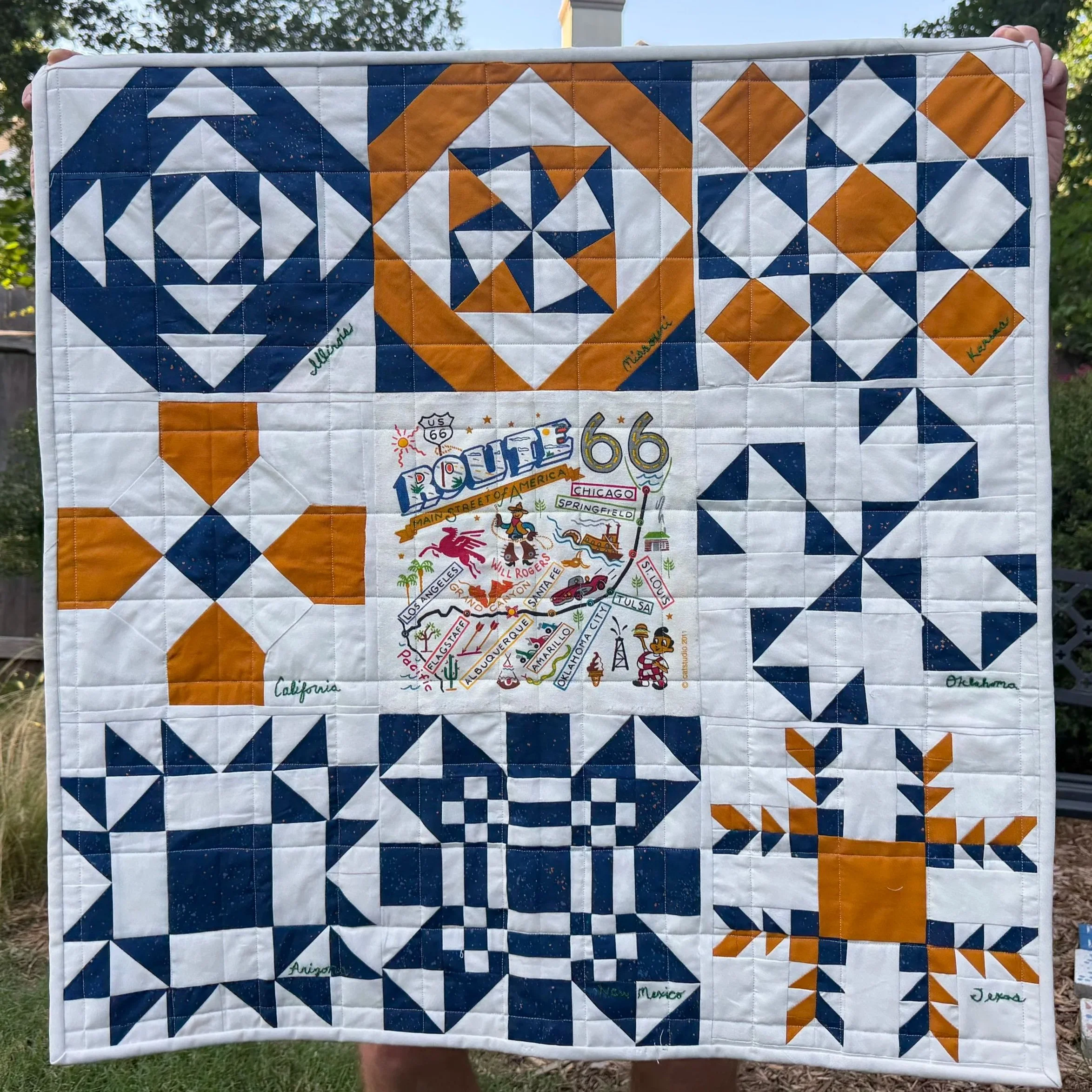 Route 66: One Block at a Time 
by Carol Williams
*
The center of this quilt is a tea towel that shows a map of the “Mother Road” and the cities along the way. Each of the neighboring blocks was made using patterns from a vintage quilt book. Each bloc