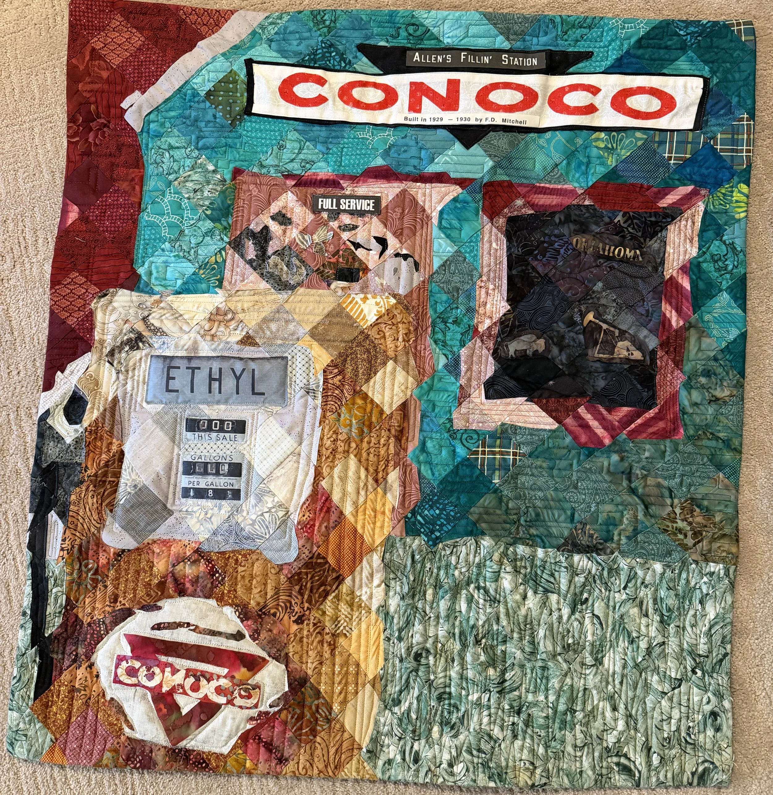 Hottest Brand Going
by Ann Makela Schneider
*
In making this quilt I reproduced a photograph I took in Miami, Oklahoma during a car trip along Route 66.  The quilt is made with 2” squares of fabric set in the diagonal.  A gas station is a fitting tri