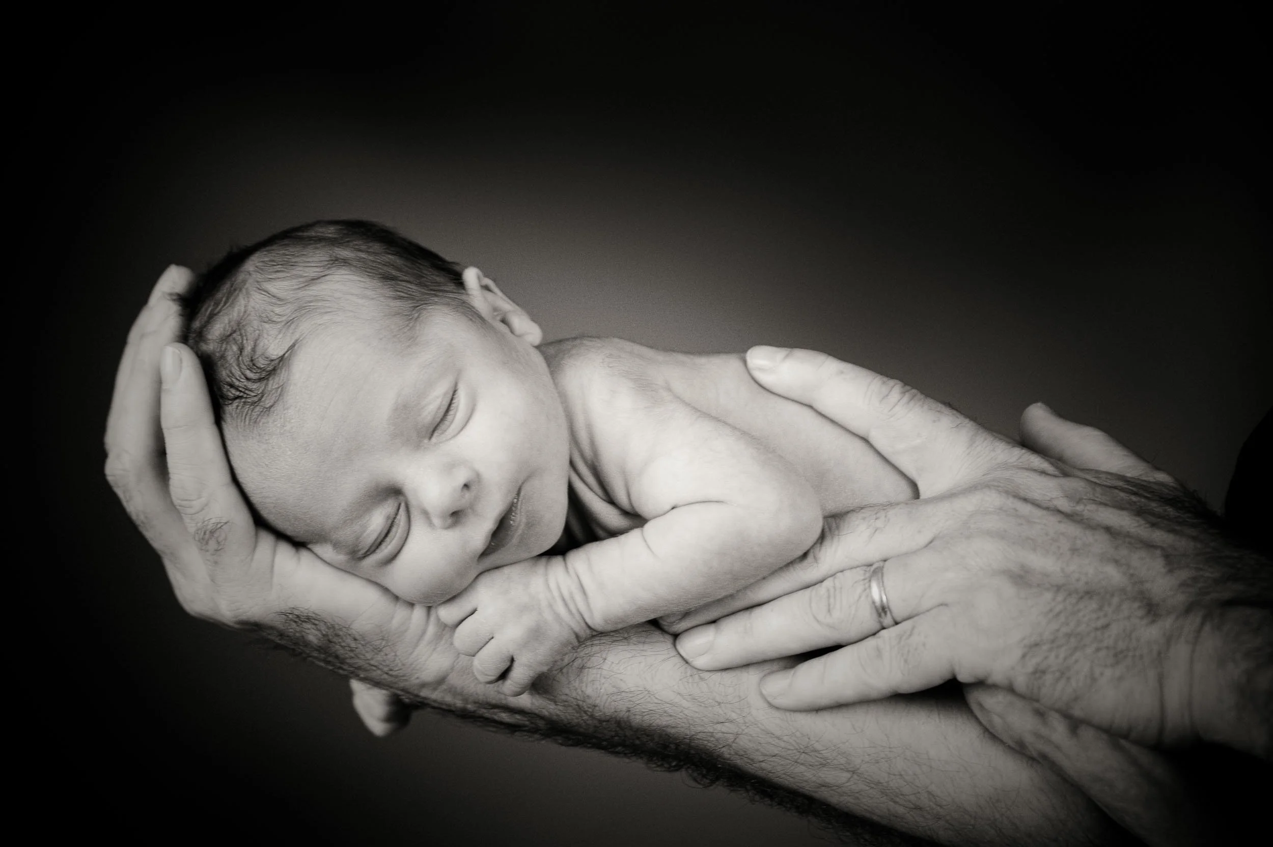 newborn baby sleeping on dad's arm