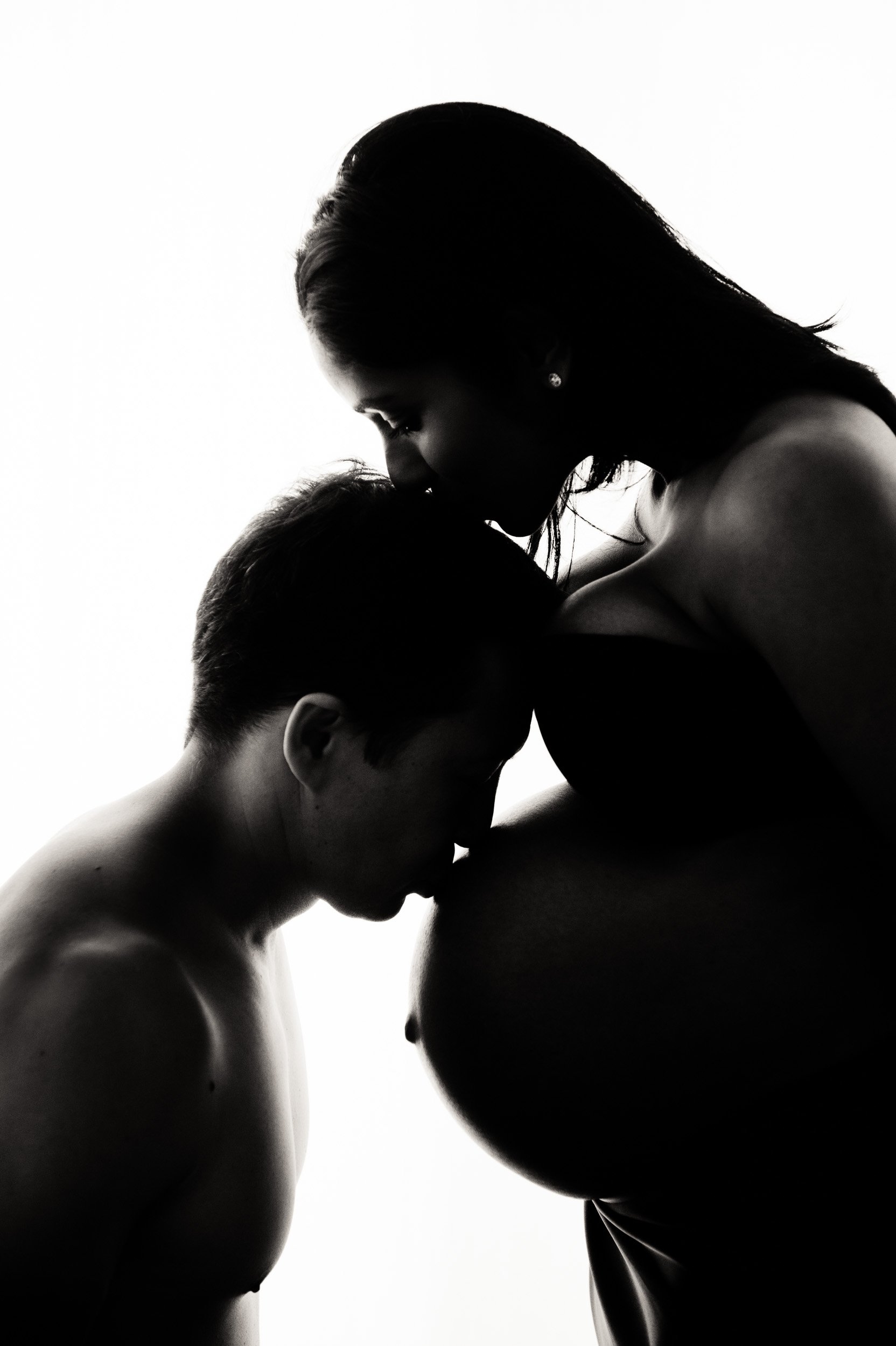 silhouette pregnancy photography of couple kissing