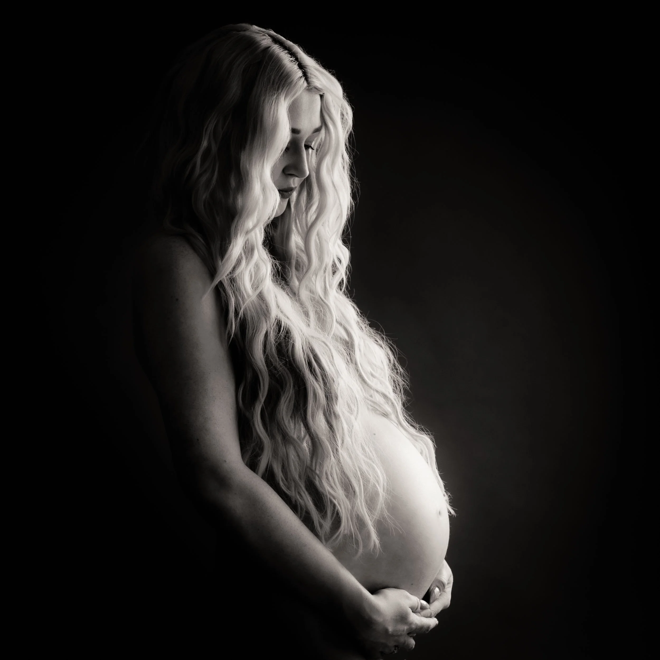 Studio Maternity Photoshoot of a woman with long hair draped over shoulders