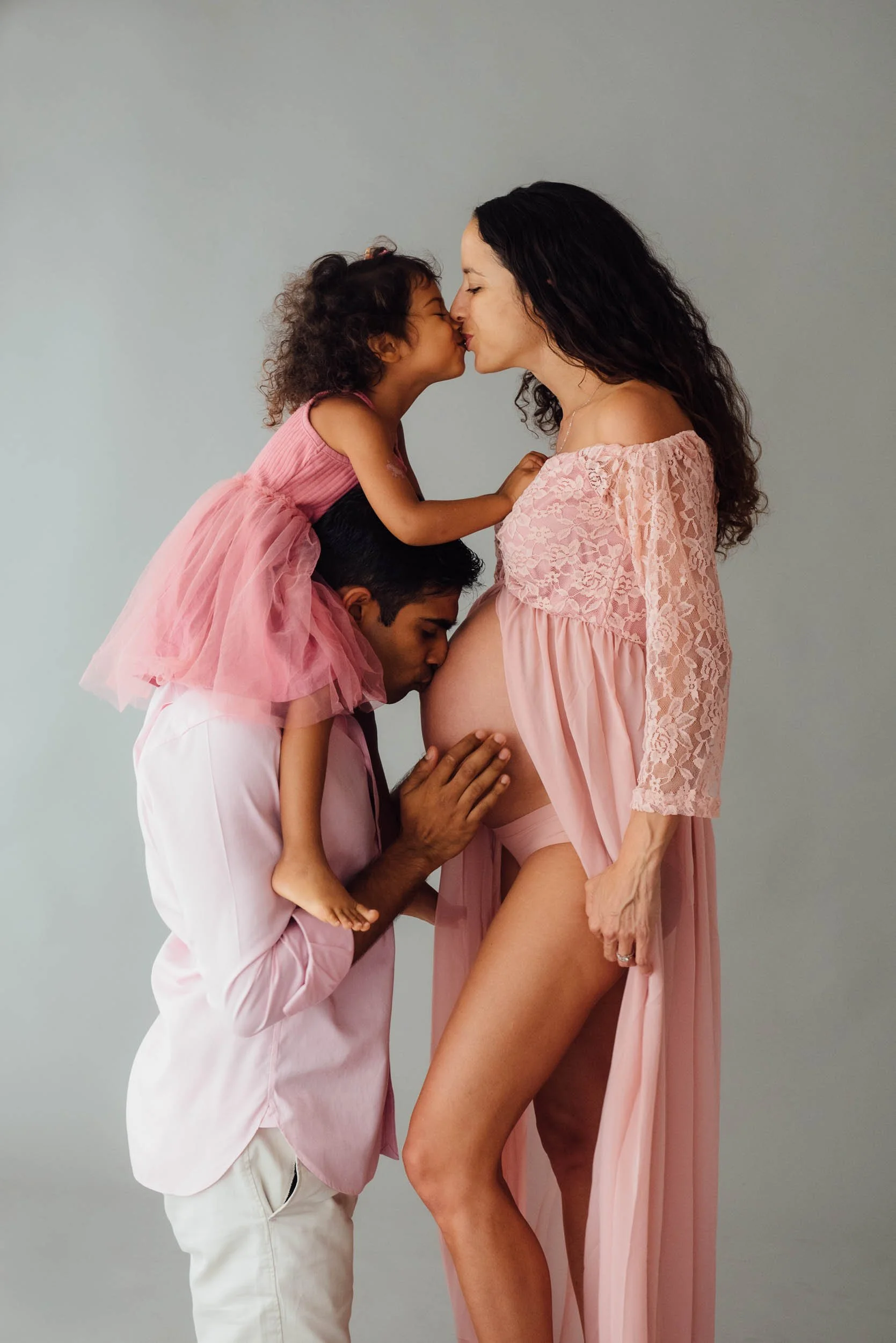 family pregnancy photoshoot of family kissing