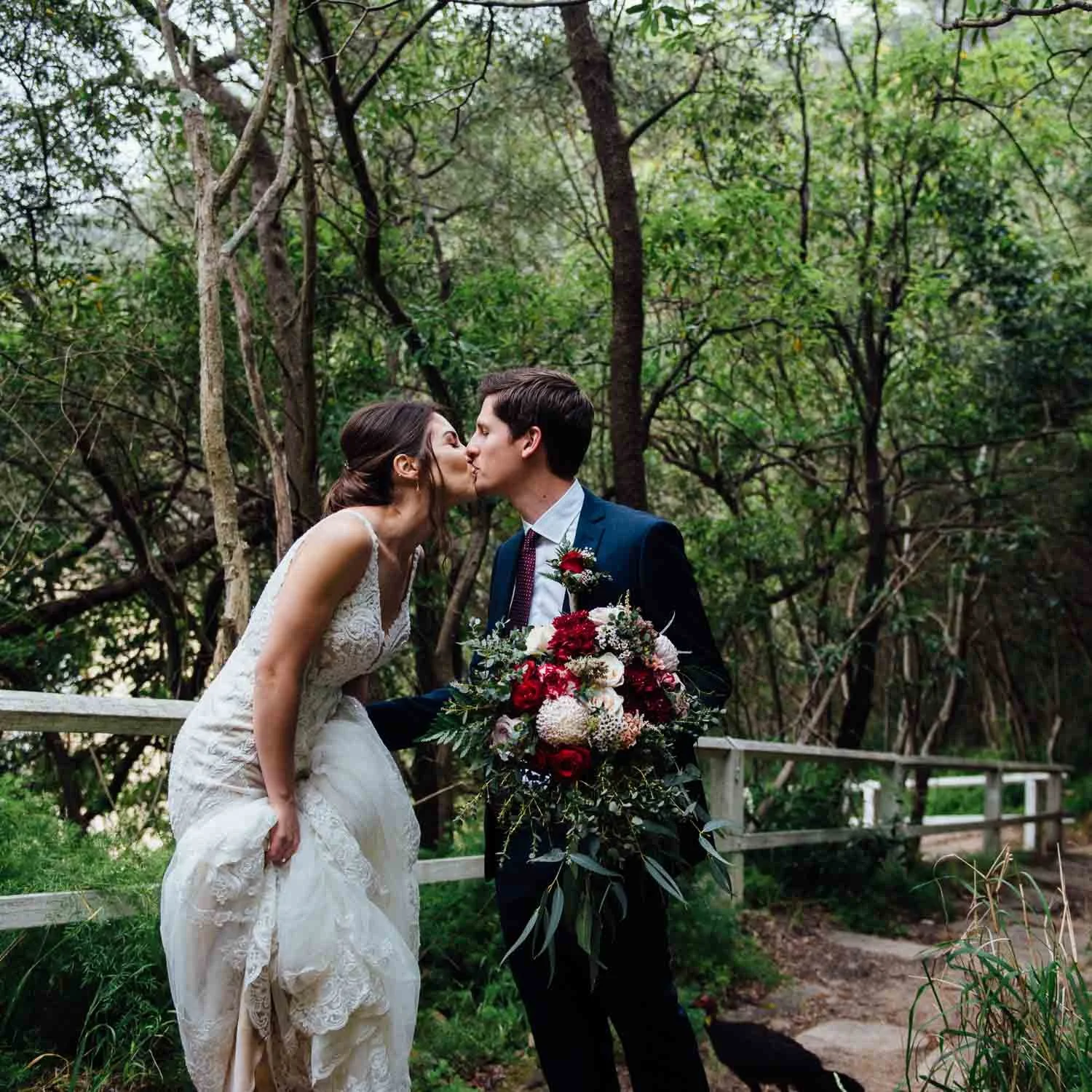 bride and groom kissing on the path to the beach at Athol Hall Wedding Photo 
