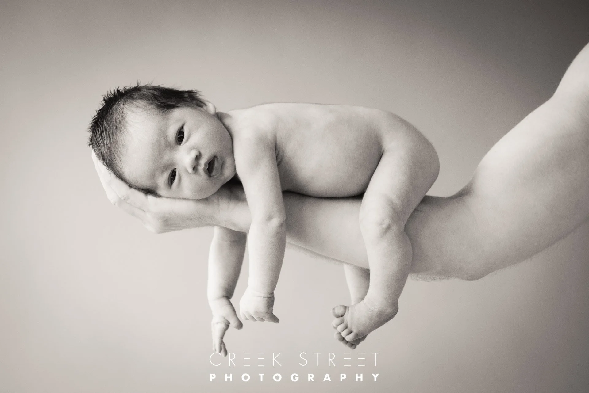 newborn photoshoot on dads arm.jpg