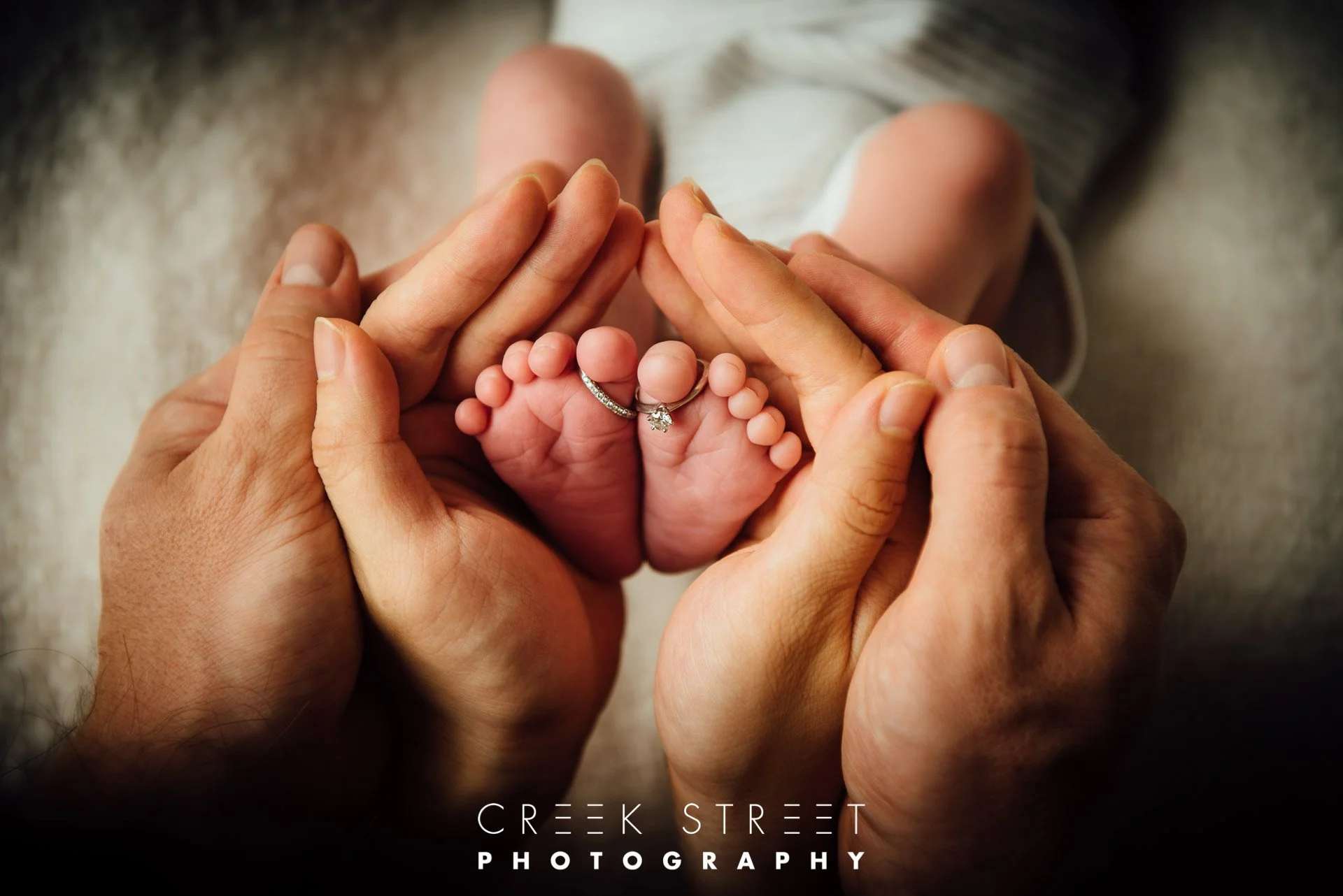 neworn feet with parents hands and wedding rings.jpg