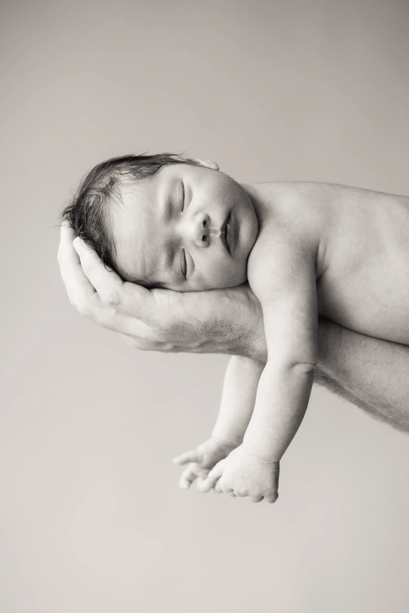 newborn photoshoot of sleeping baby lying on fathers arm
