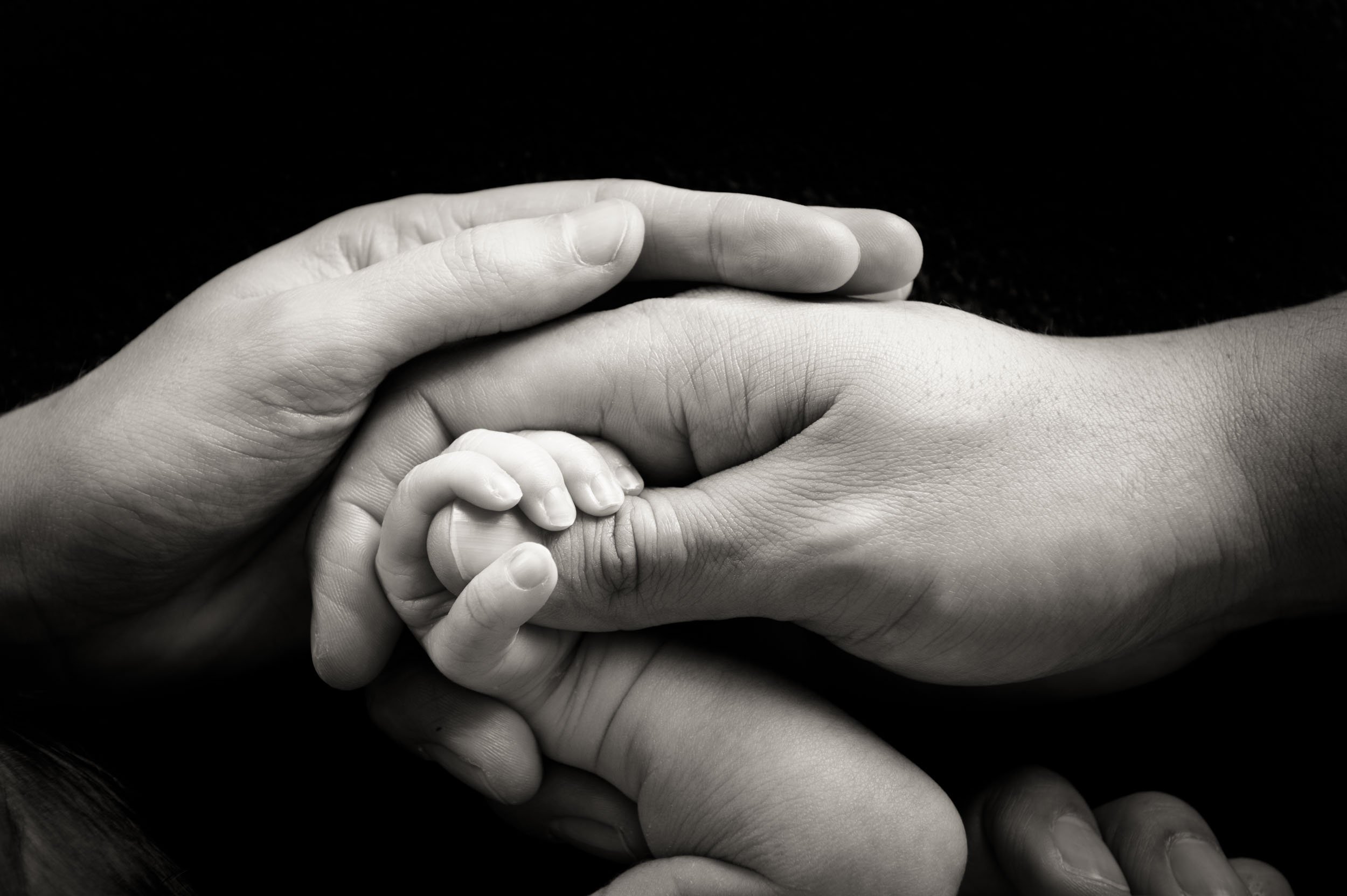 newborn photography of parents and baby holding hands close up