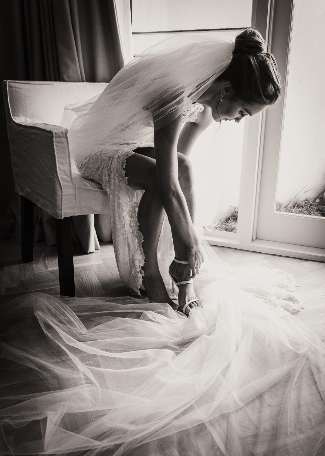 Bride putting her shoes on black and white wedding photo