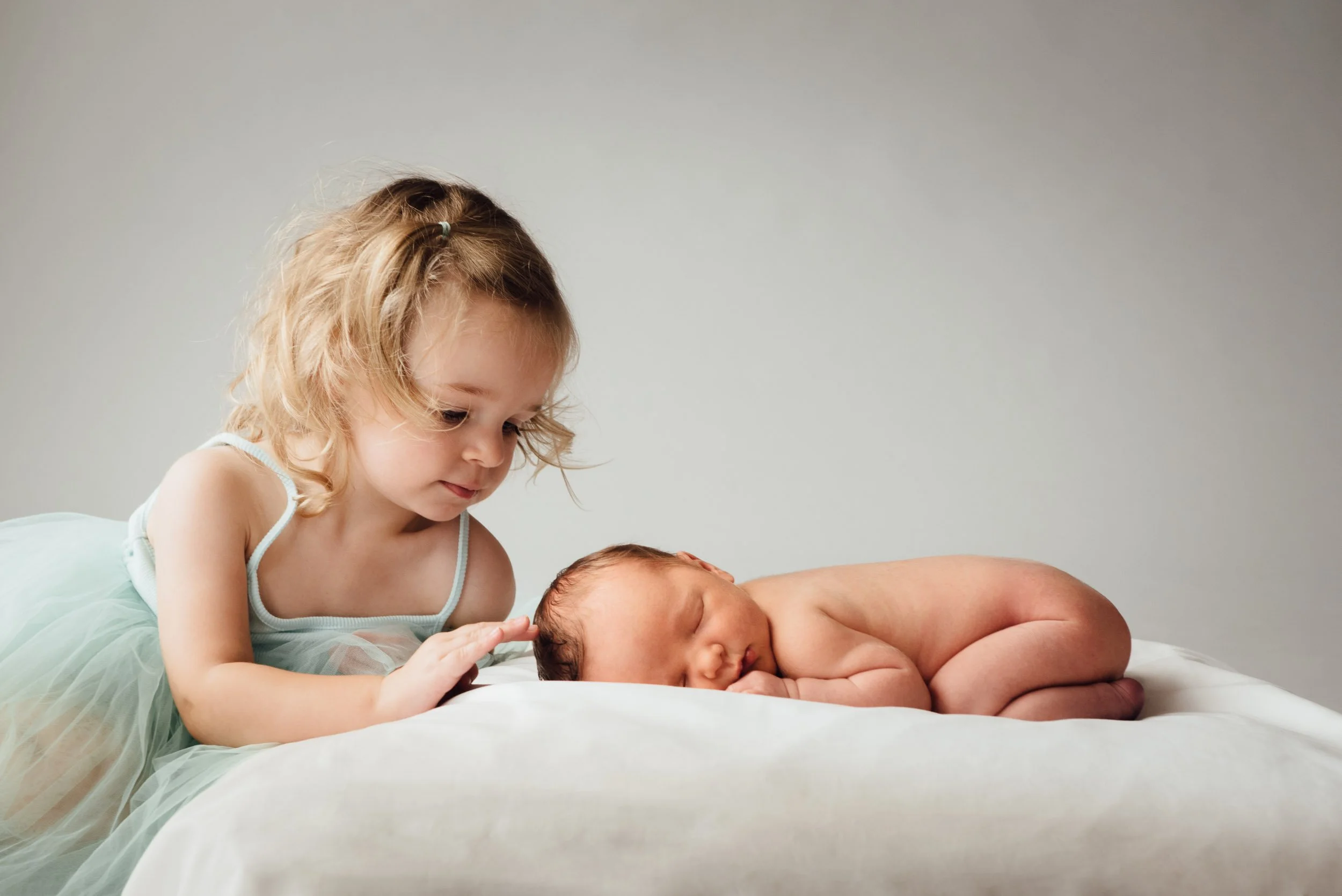 newborn photography of big sister stroking her sleeping brother's head