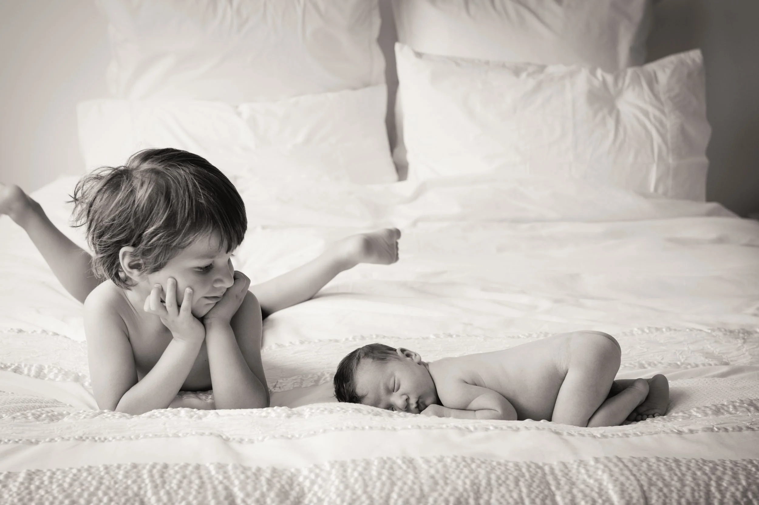 newborn photography home session of baby and big brother lying on parents bed