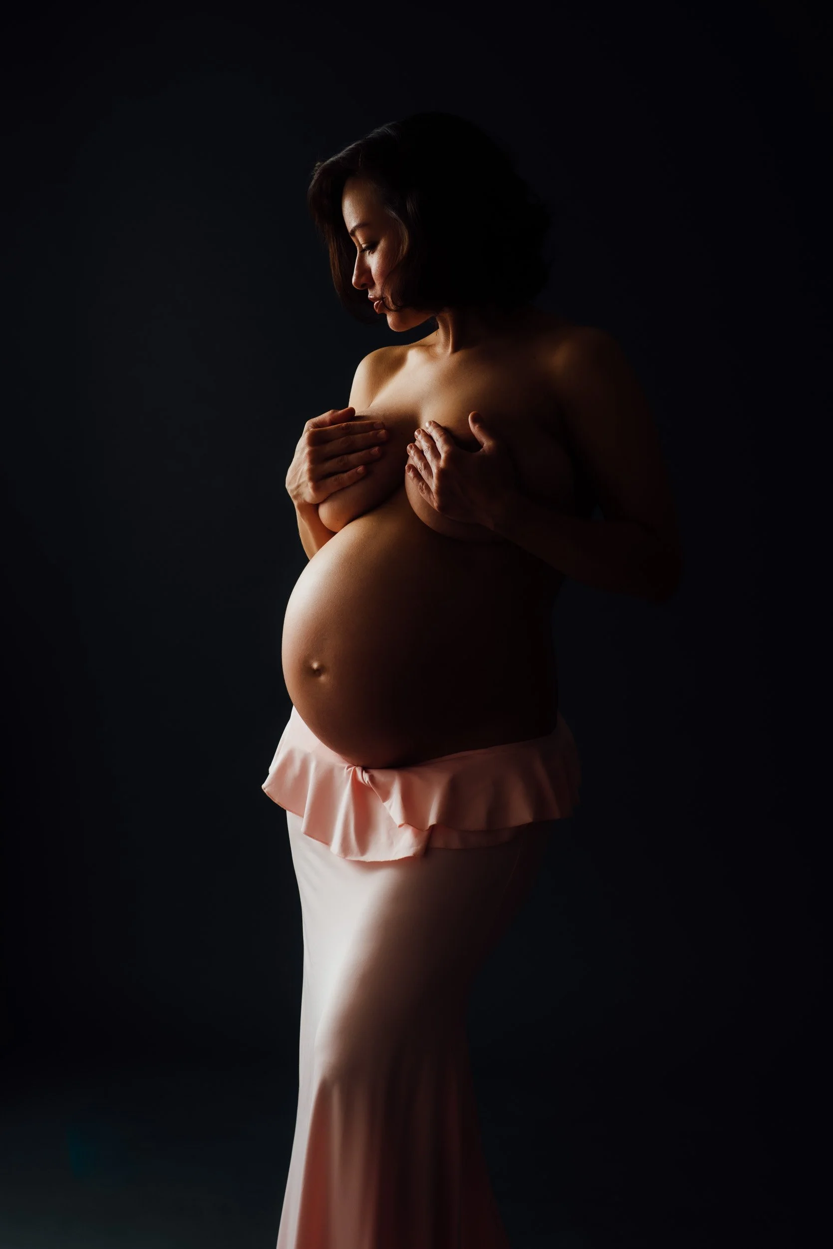 Maternity photoshoot of woman in a long pink skirt
