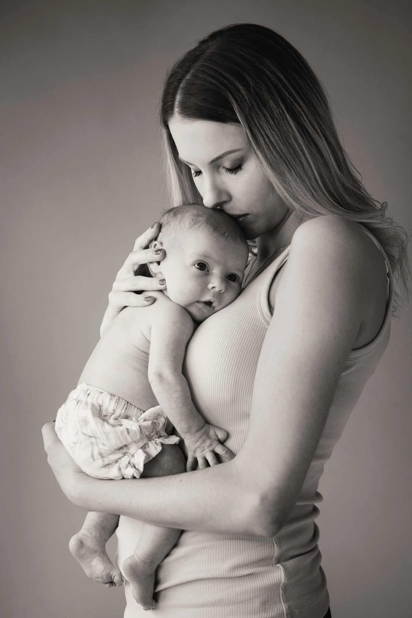 mother kissing daughter during a newborn photoshoot