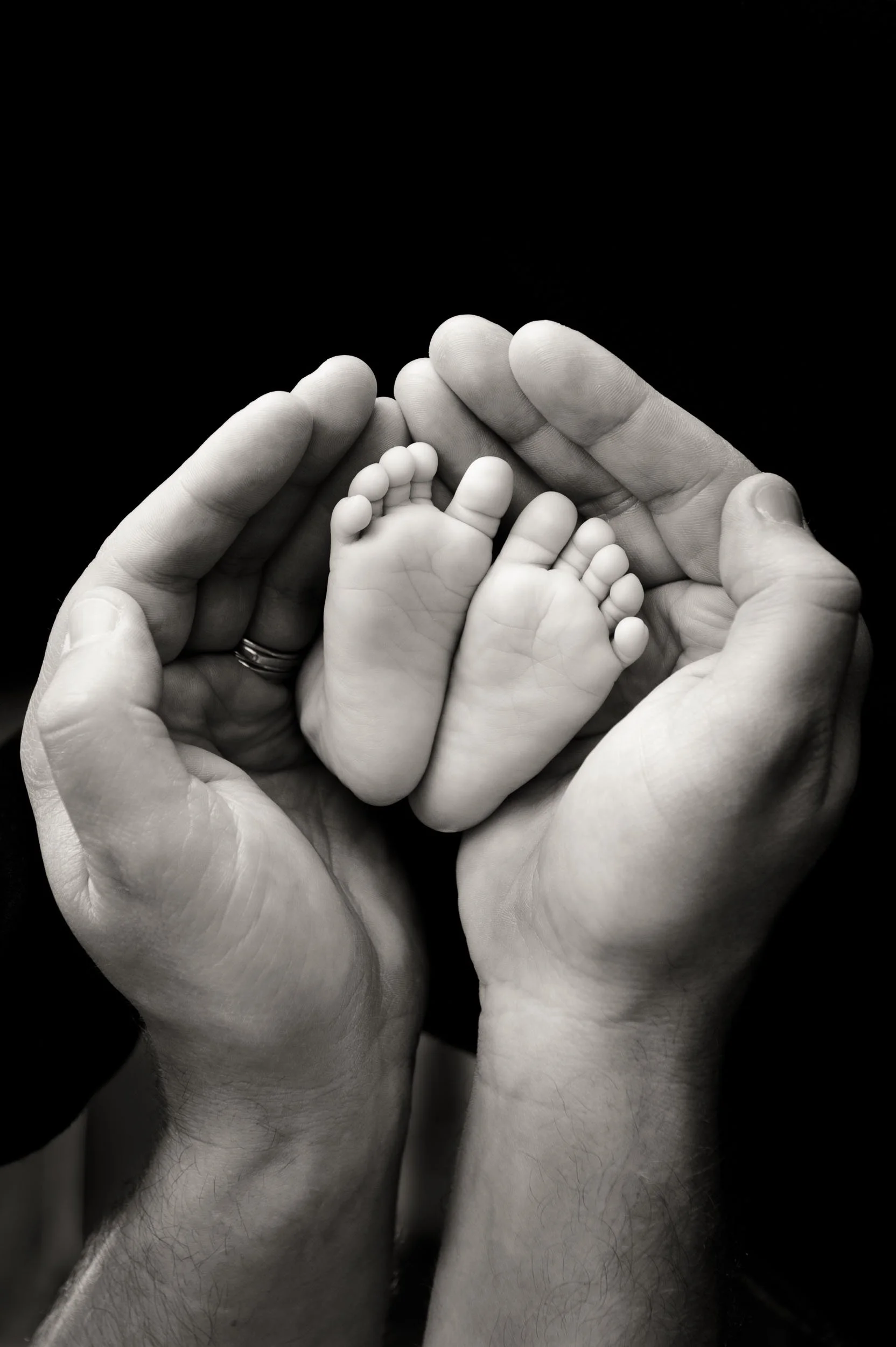 newborn feet photography of fathers hands holding baby's feet