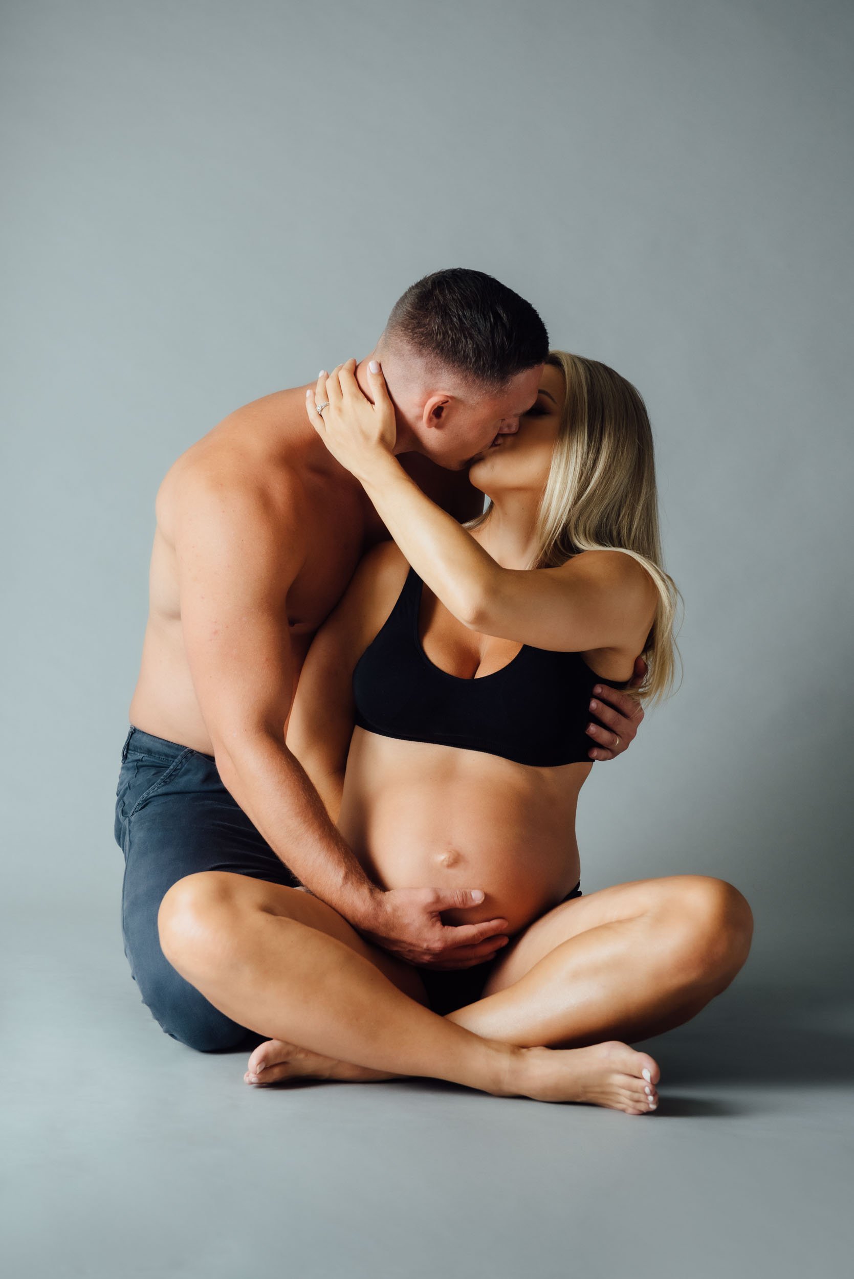 pregnancy photography Sydney shoot of couple sitting on floor kissing
