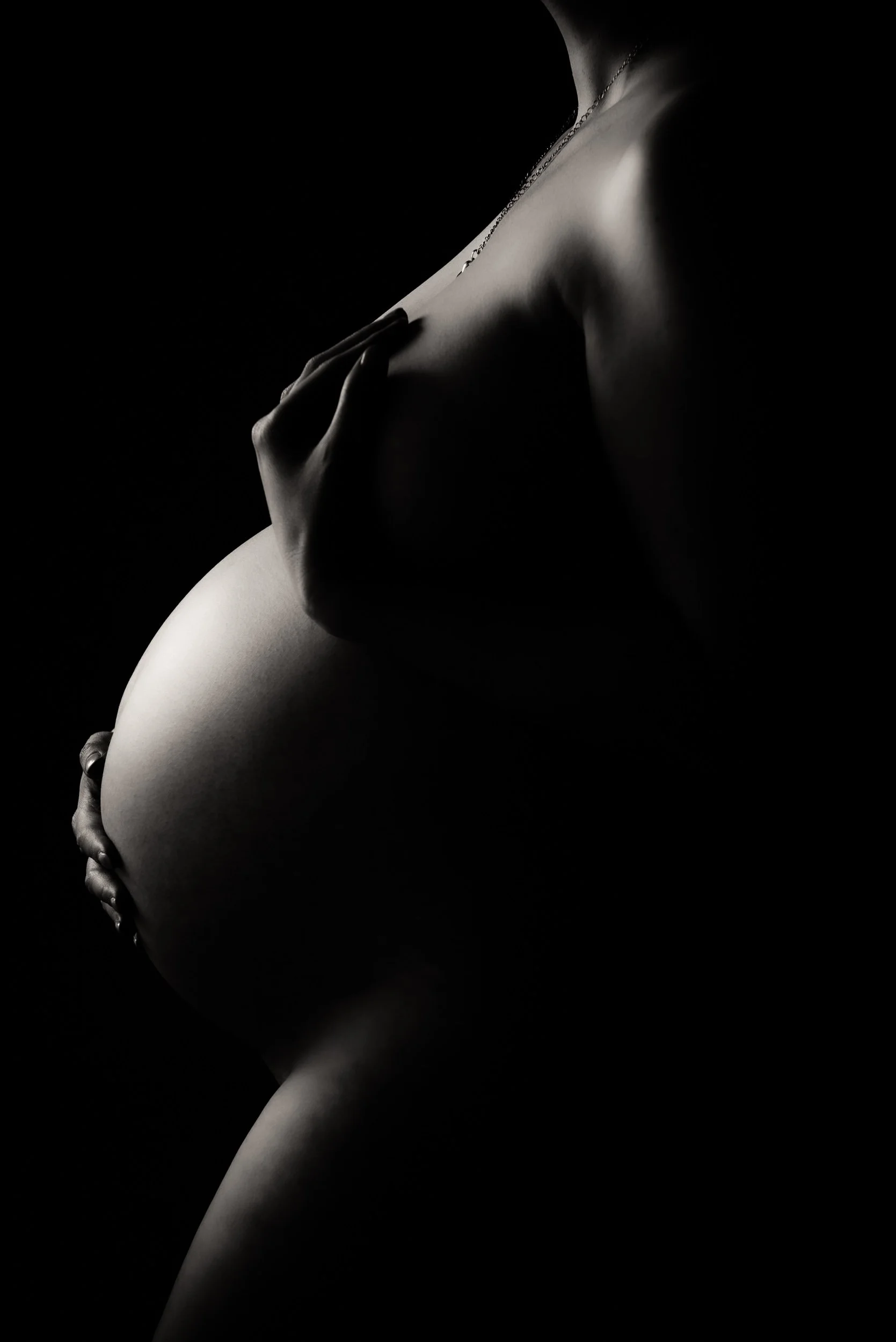 close up portrait of pregnant belly close back lit