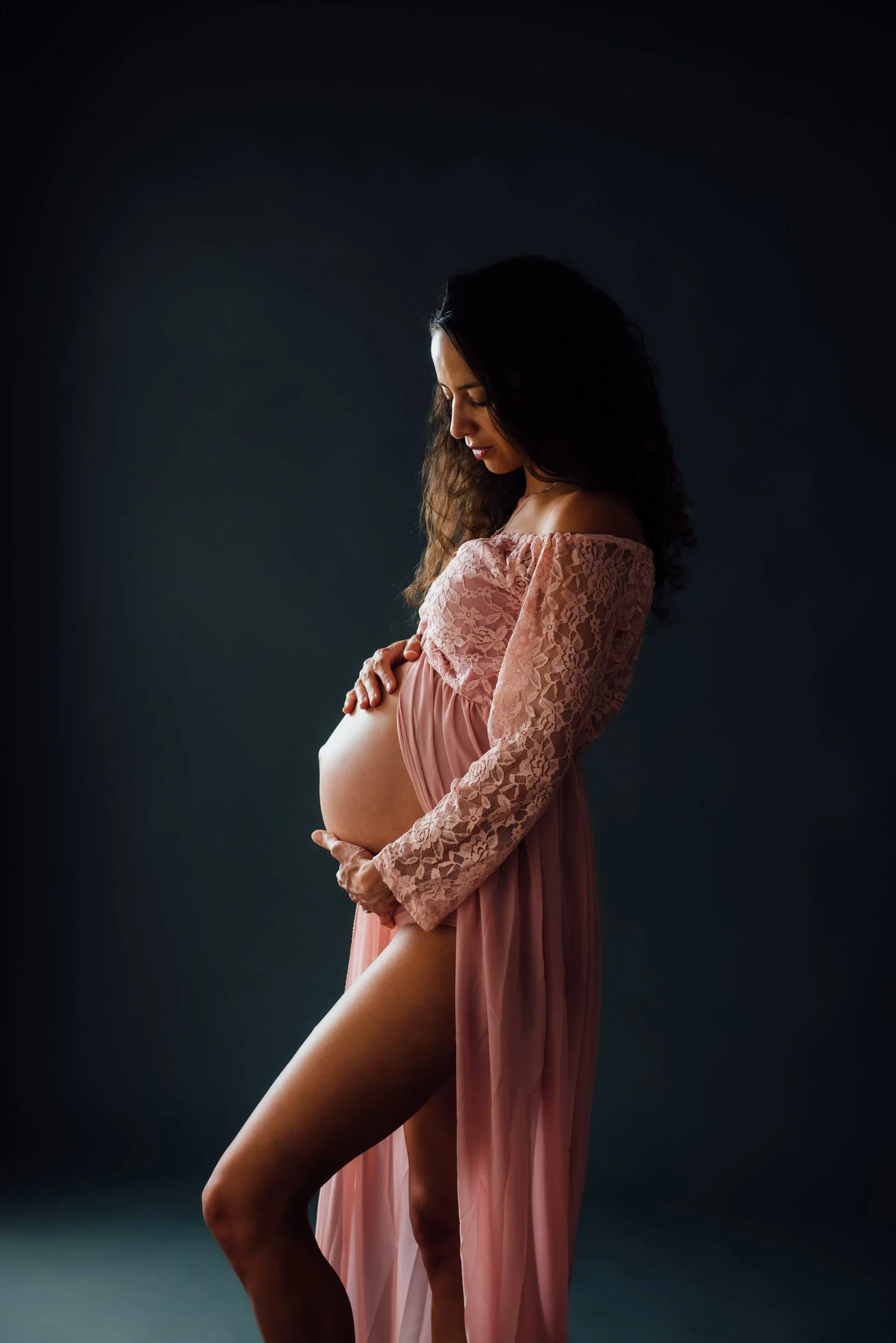 Maternity photography of a woman in a pink lace dress