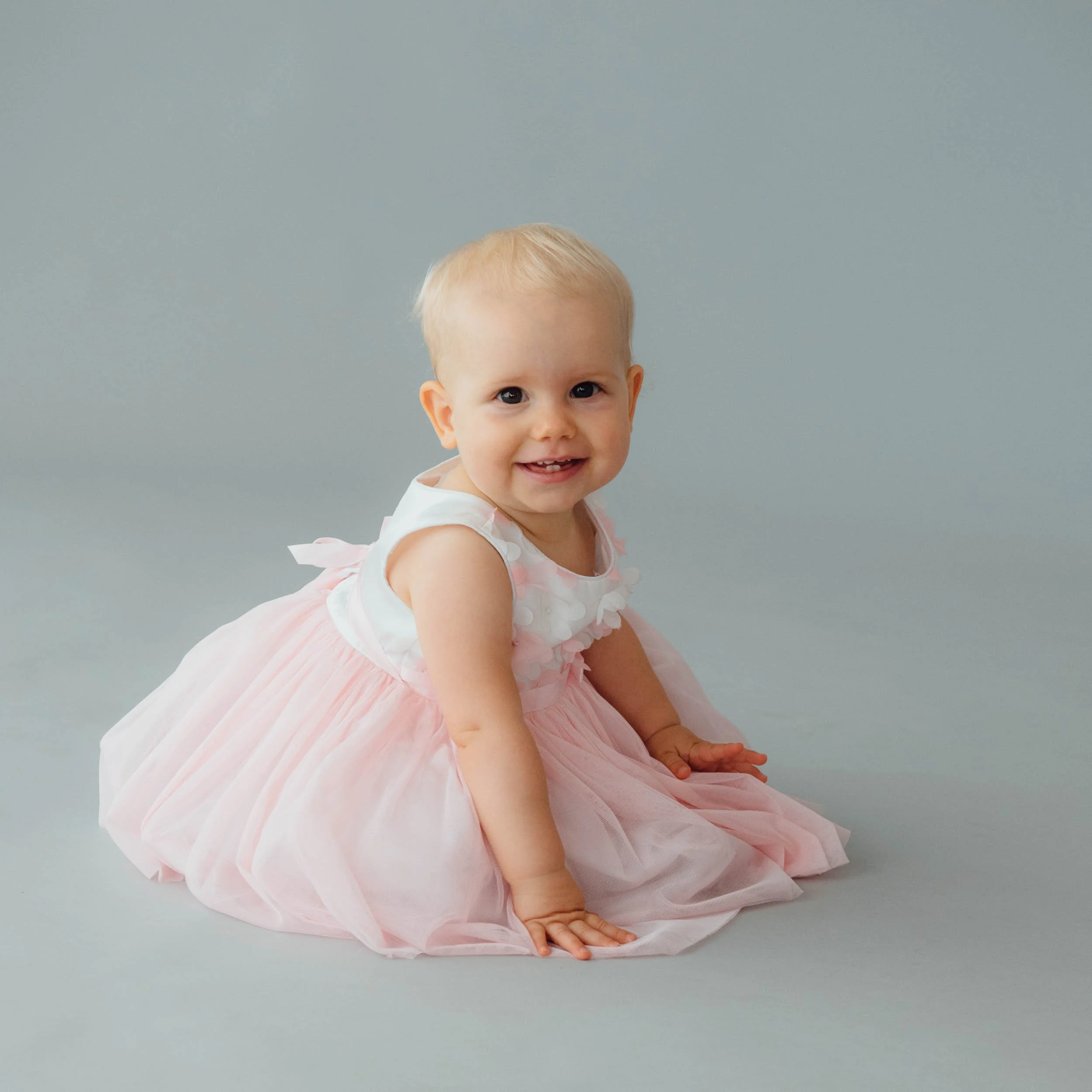 one year old baby photography of girl in pretty pink dress