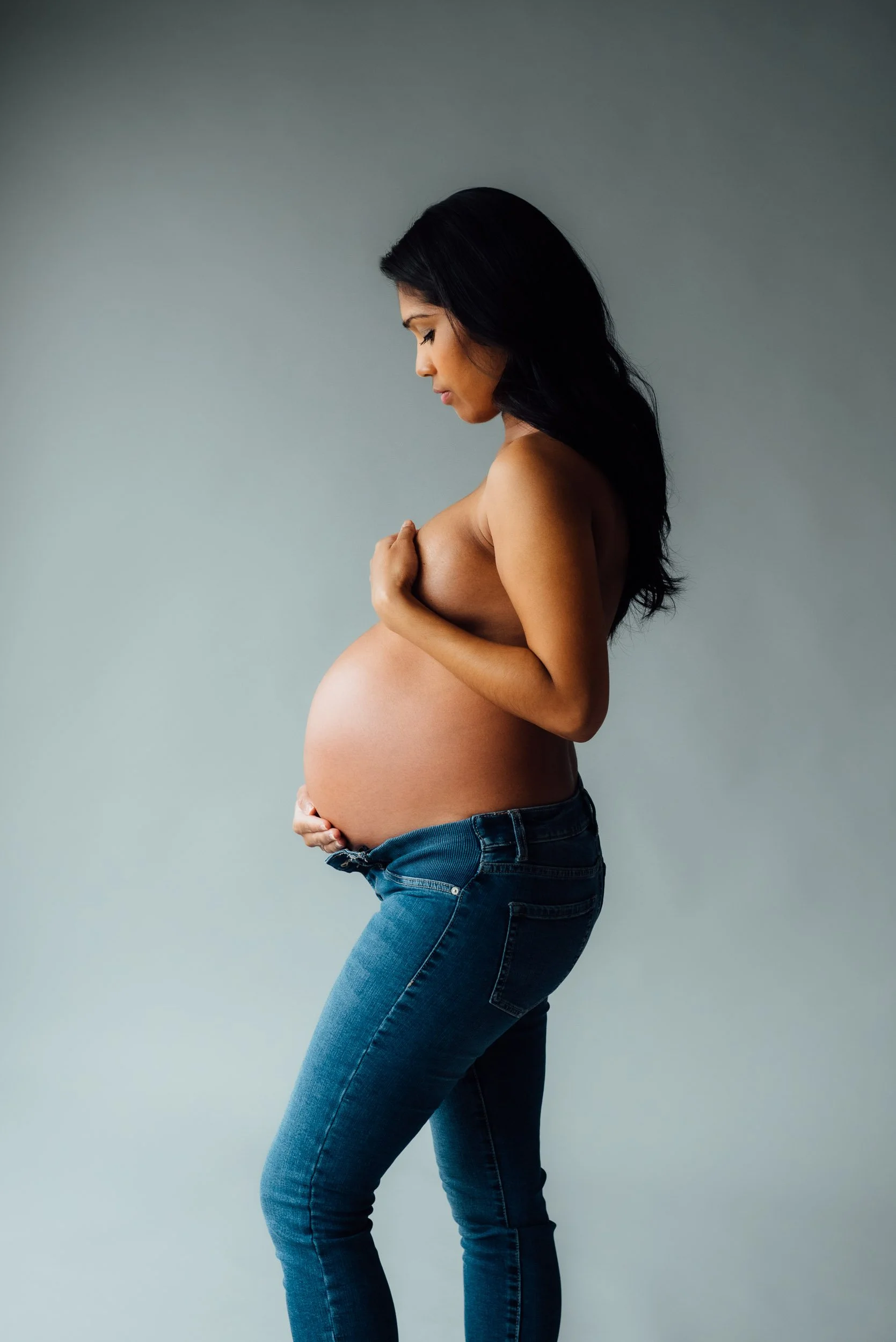Elegant pregnancy photo of a woman in blue jeans