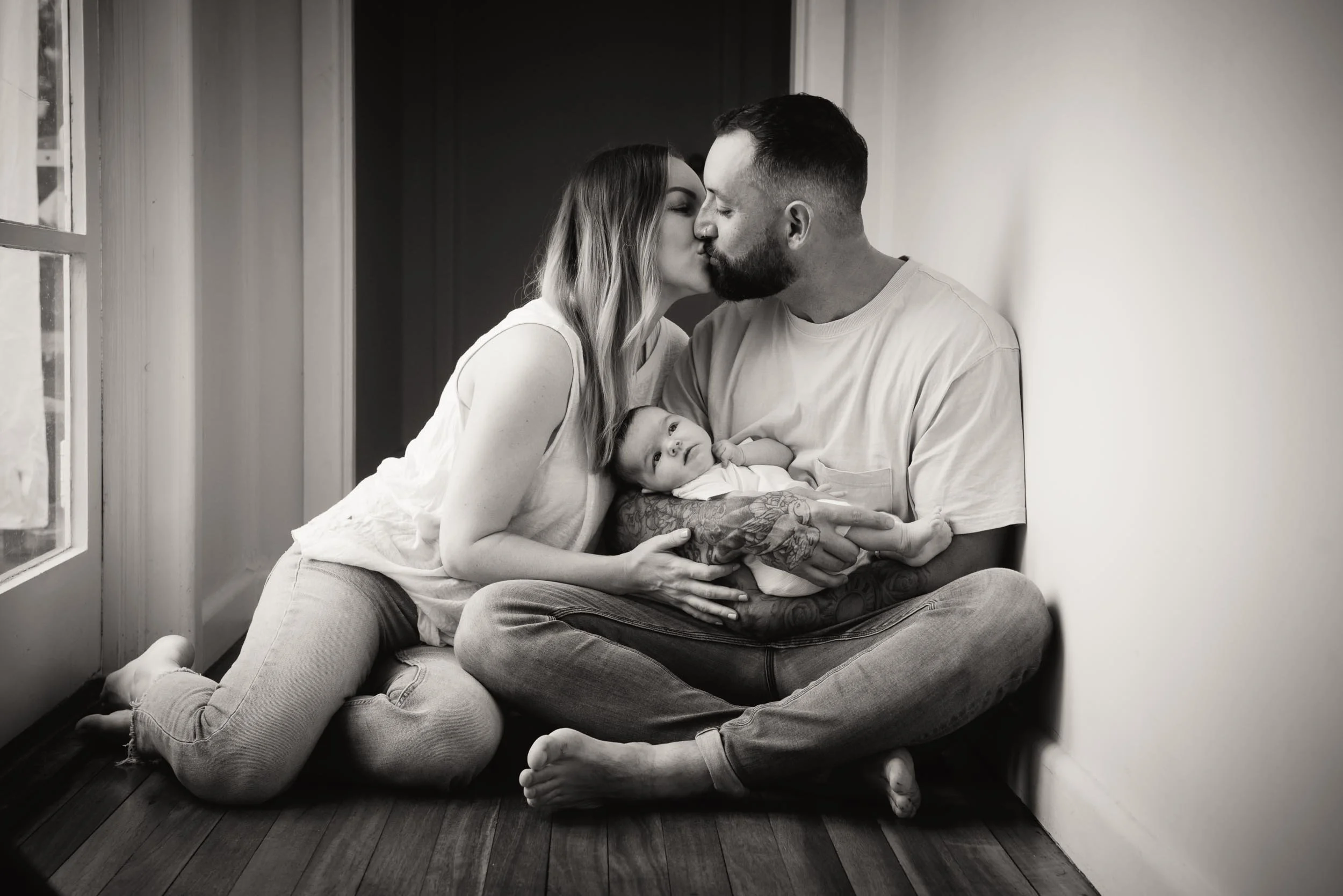 parents kissing while holding their baby in photography studio