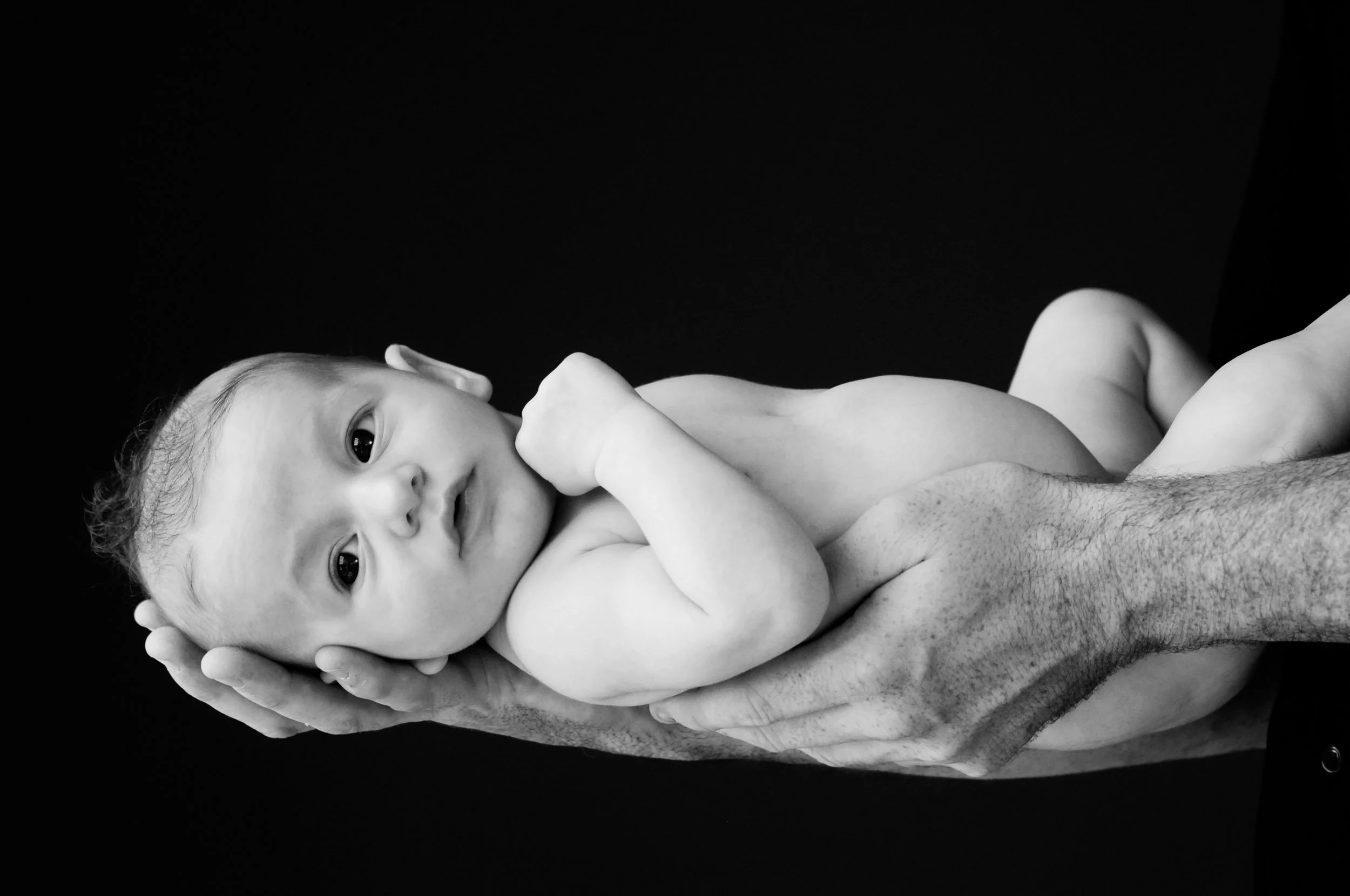 newborn photography of baby lying on father's arm